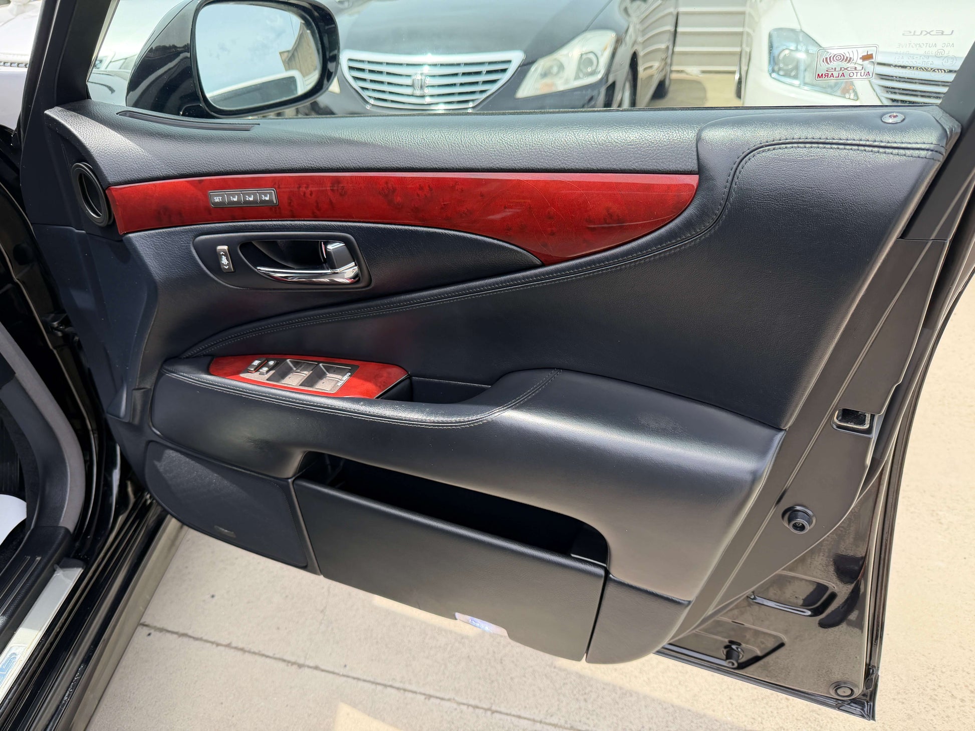 Interior view of the 2007 Lexus LS600hL AWD V8 5.0L Hybrid luxury sedan door with wood accents and control features.