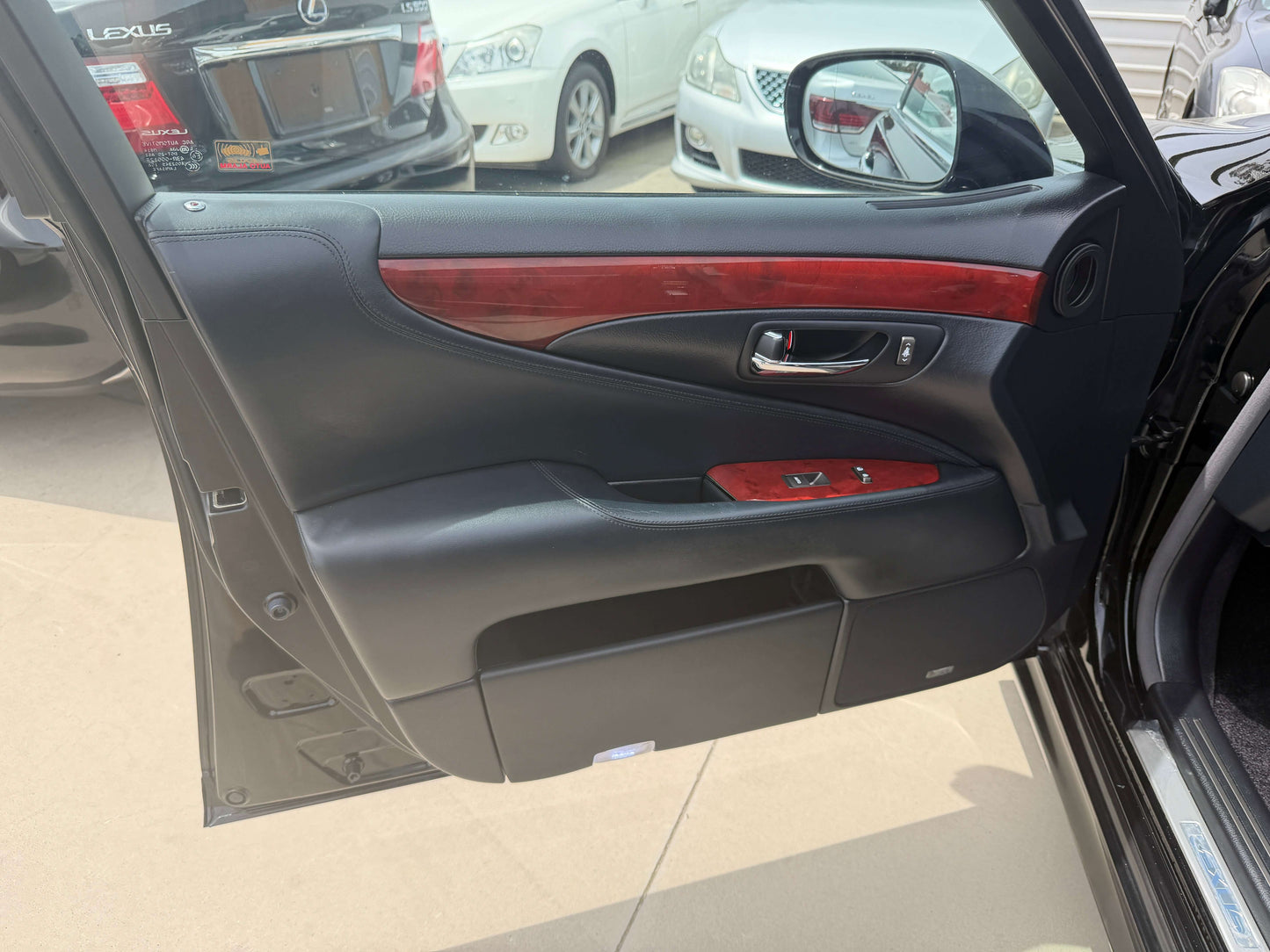 Interior view of the 2007 Lexus LS600hL AWD V8 5.0L Hybrid luxury sedan door panel featuring wood trim and controls.