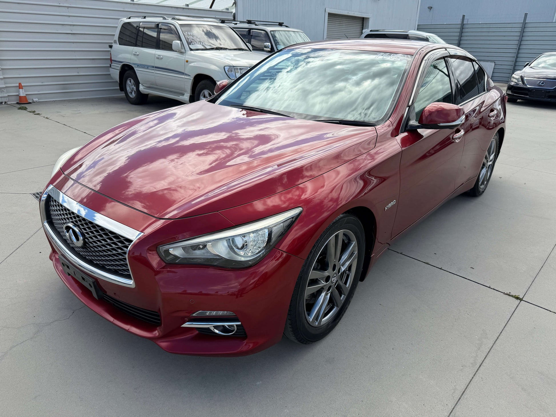 2015 Nissan Skyline V6 3.5L Hybrid in deep red color showcasing sporty design and hybrid efficiency.