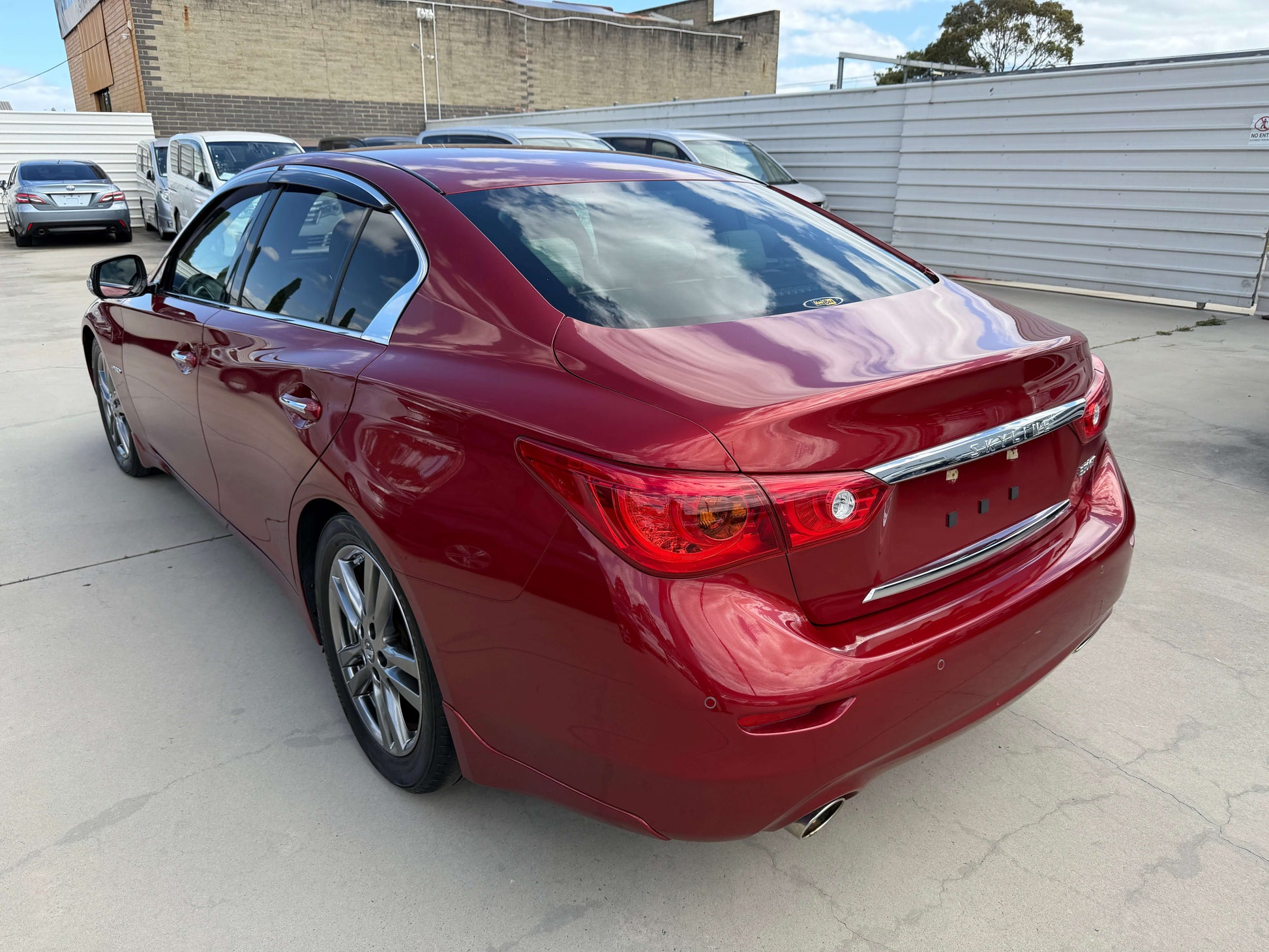 2015 Nissan Skyline V6 3.5L Hybrid Sport Sedan in deep red showcasing stylish design and sporty contours.