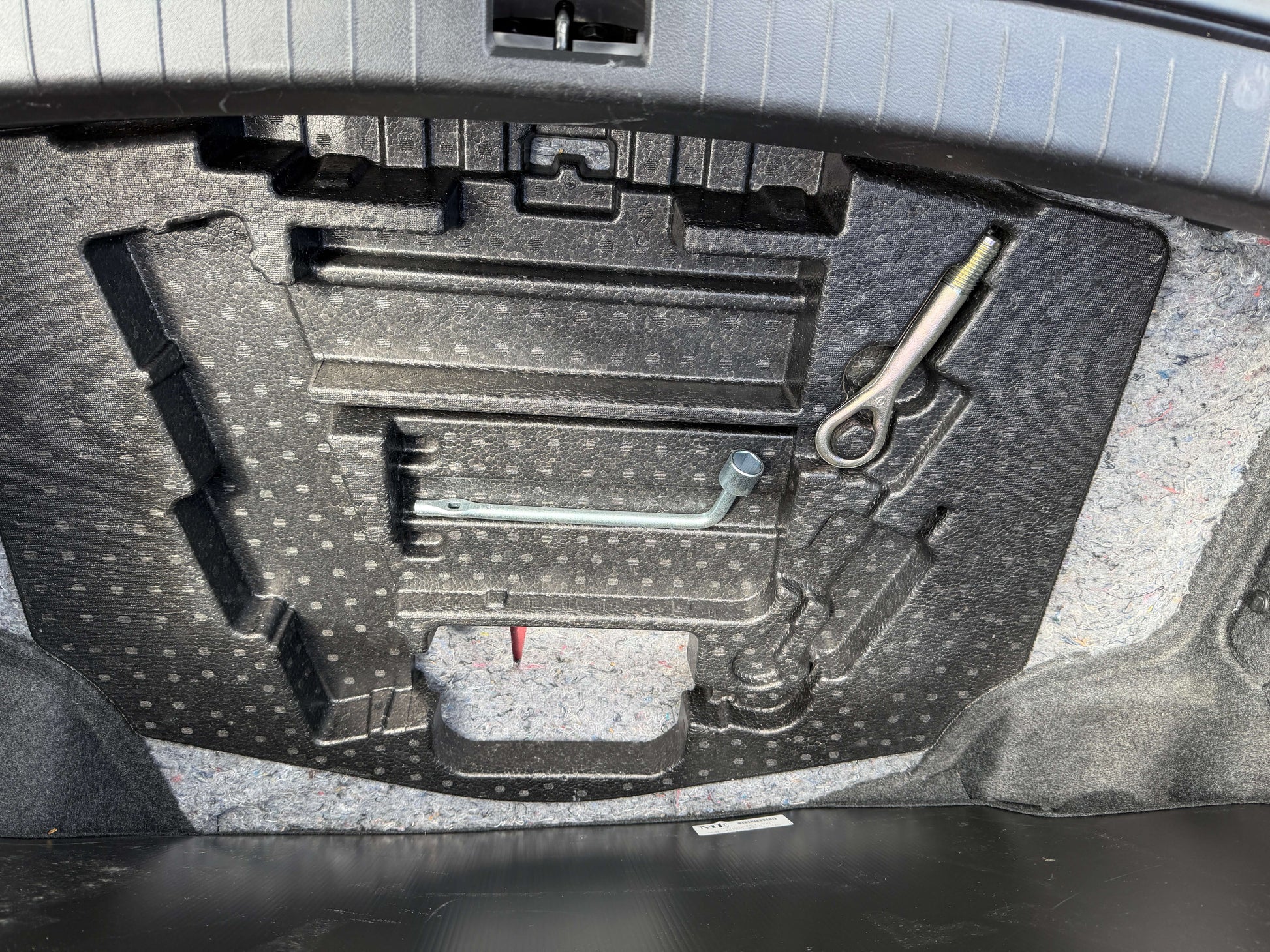 Interior view of the trunk space in a 2015 Nissan Skyline V6 3.5L Hybrid, showcasing tools and storage layout.