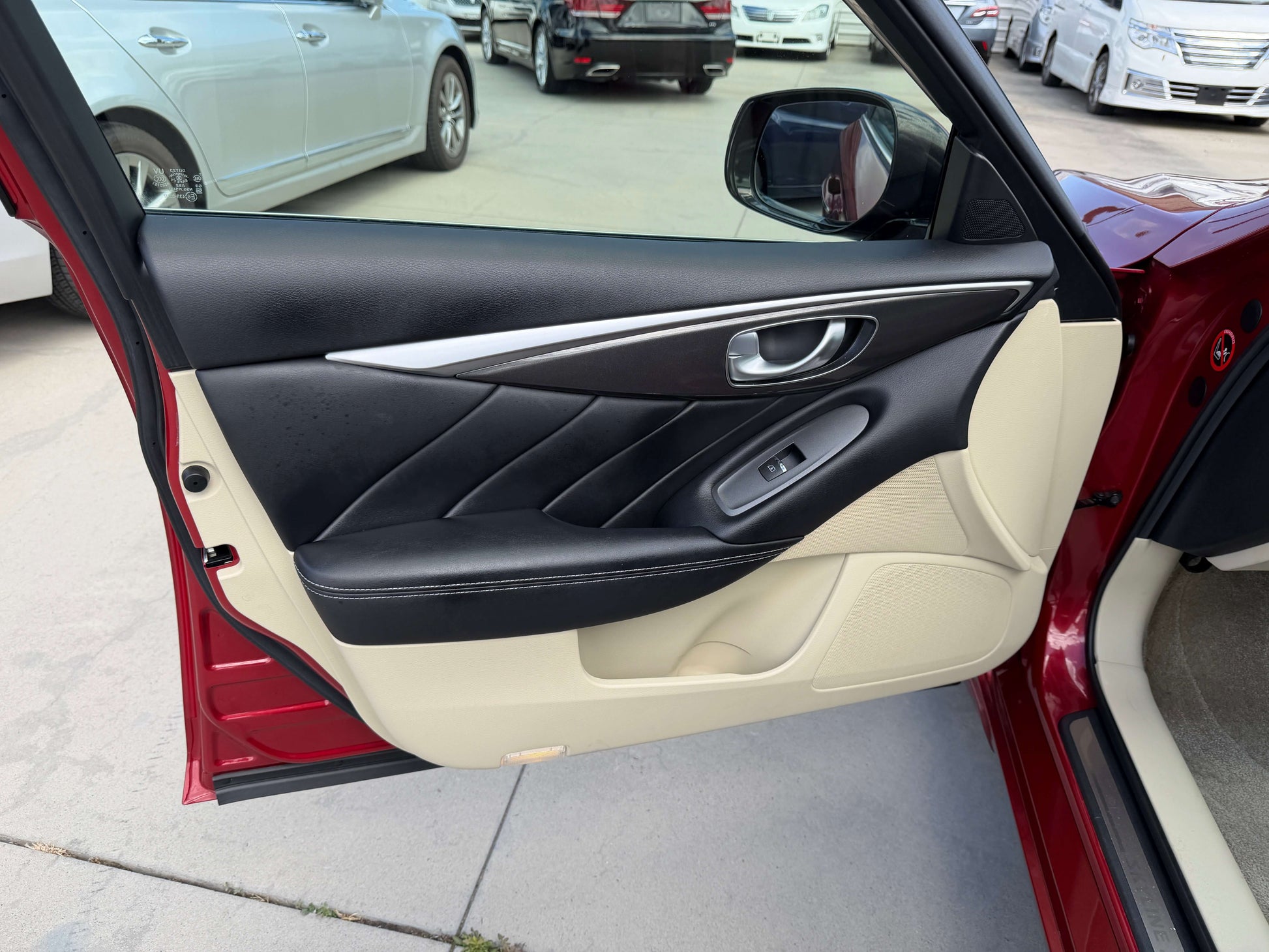 Interior door panel of a 2015 Nissan Skyline V6 3.5L Hybrid showcasing stylish black and beige design.