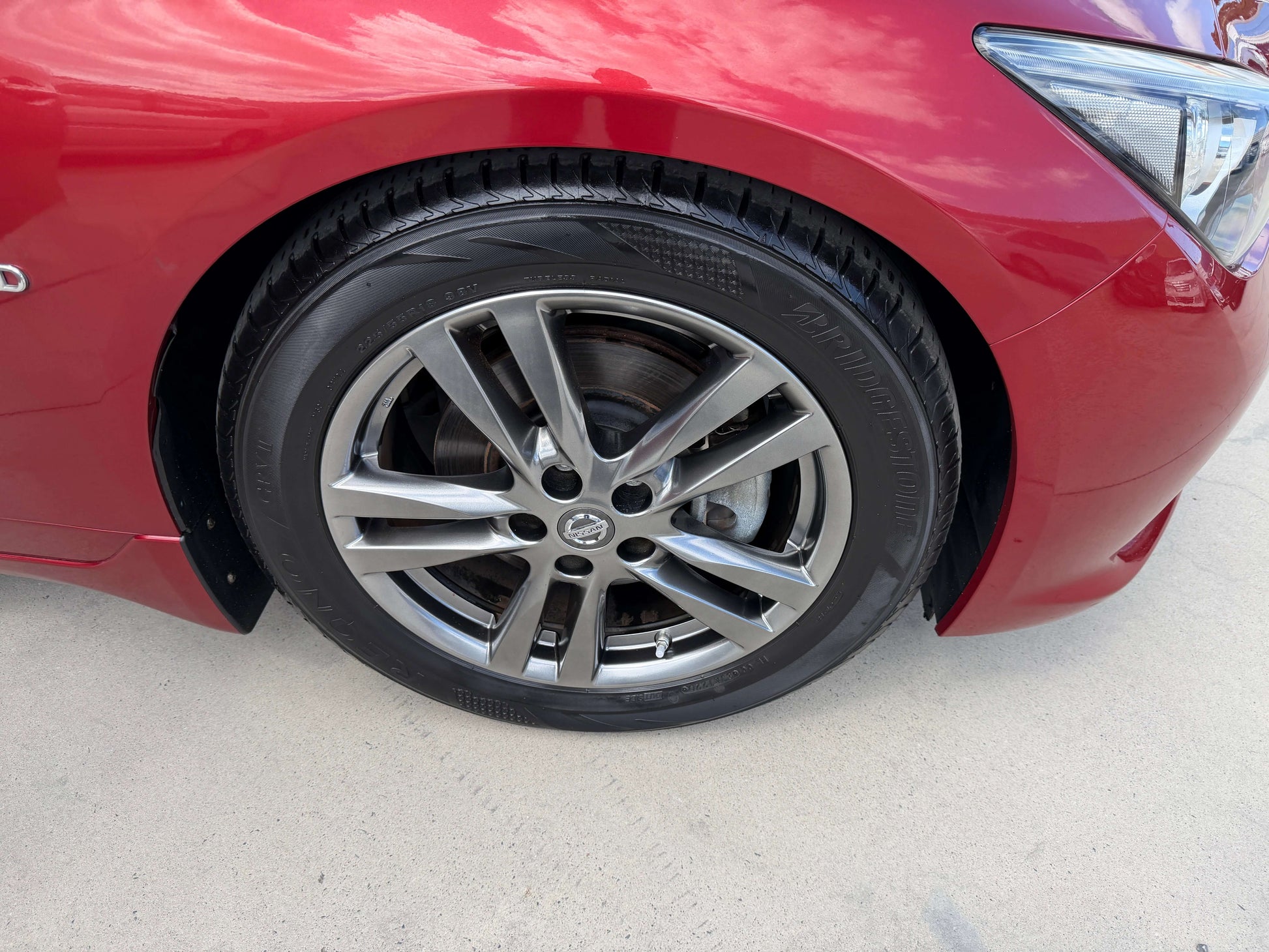 Close-up of the wheel on a 2015 Nissan Skyline V6 3.5L Hybrid Sport Sedan, showcasing stylish alloy design and tires.