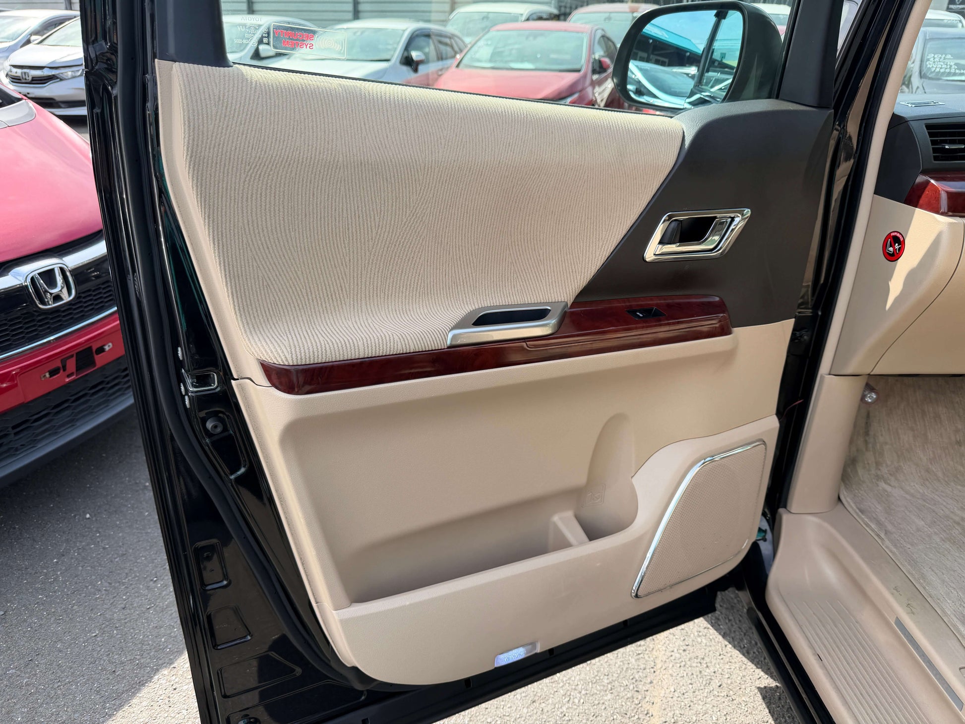 Interior view of the 2010 Toyota Vellfire 2.4L V Edition door panel with beige upholstery and wood trim.
