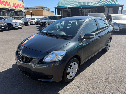 2010 Toyota Yaris 1.5L YRS Auto sedan in dark gray, parked in a car lot with a clear sky.