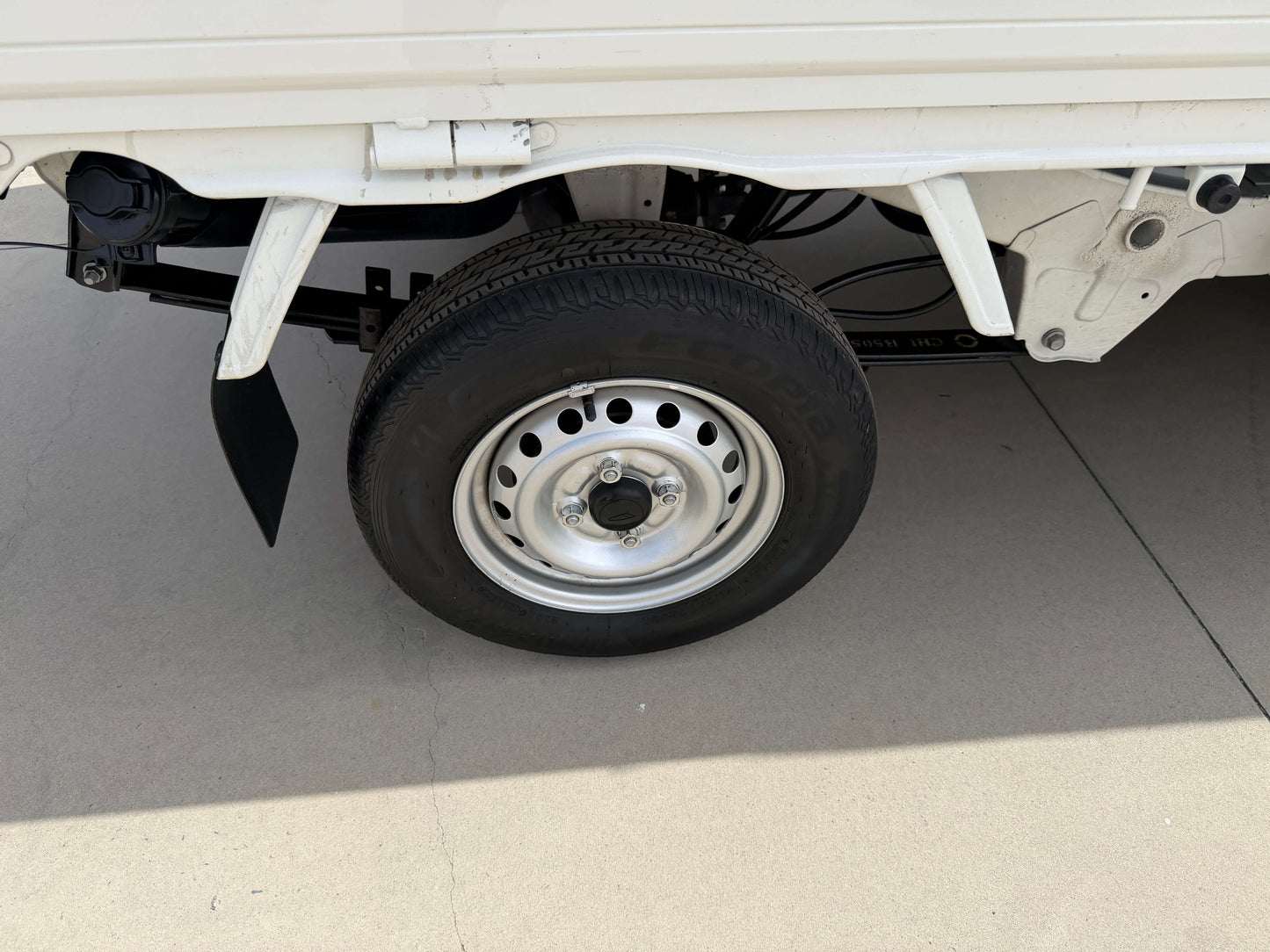 Wheel of a 2021 Daihatsu Hijet Truck 660 Jumbo SA IIIt, showcasing tire details and part of the truck's body.