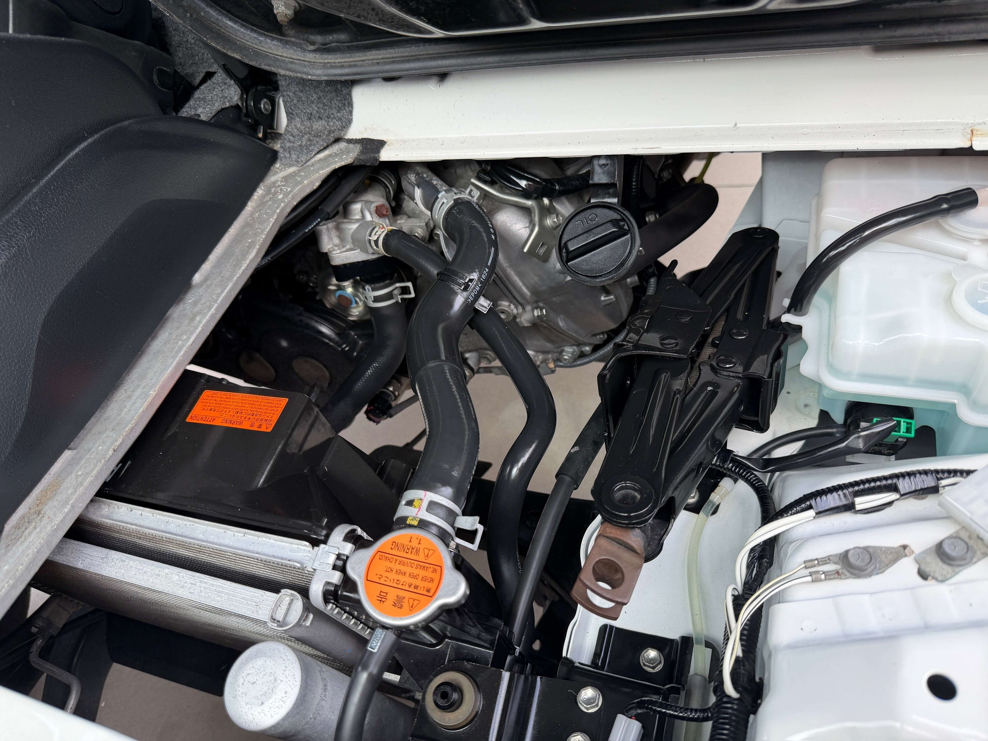 Engine compartment of a 2021 Daihatsu Hijet Truck 660 showing internal components and layout.
