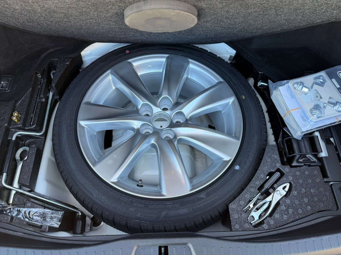 2007 Lexus LS600h AWD V8 5.0L Hybrid Spare wheel and tire tools in the trunk of a vehicle, complete with silver alloy wheel and equipment for changing a tire.