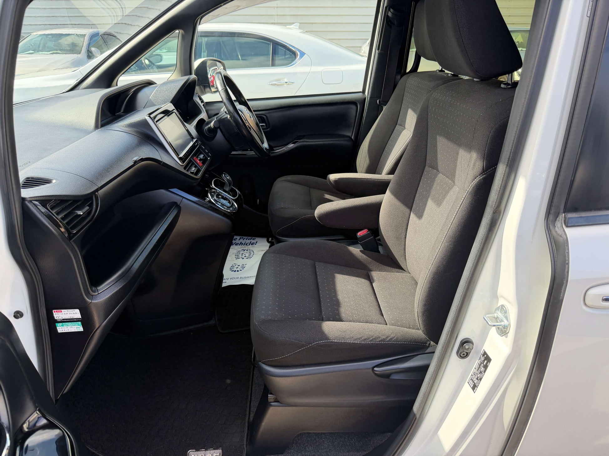 Interior view of a 2018 Toyota Noah 1.8L Hybrid showing spacious front seats and modern dashboard design.