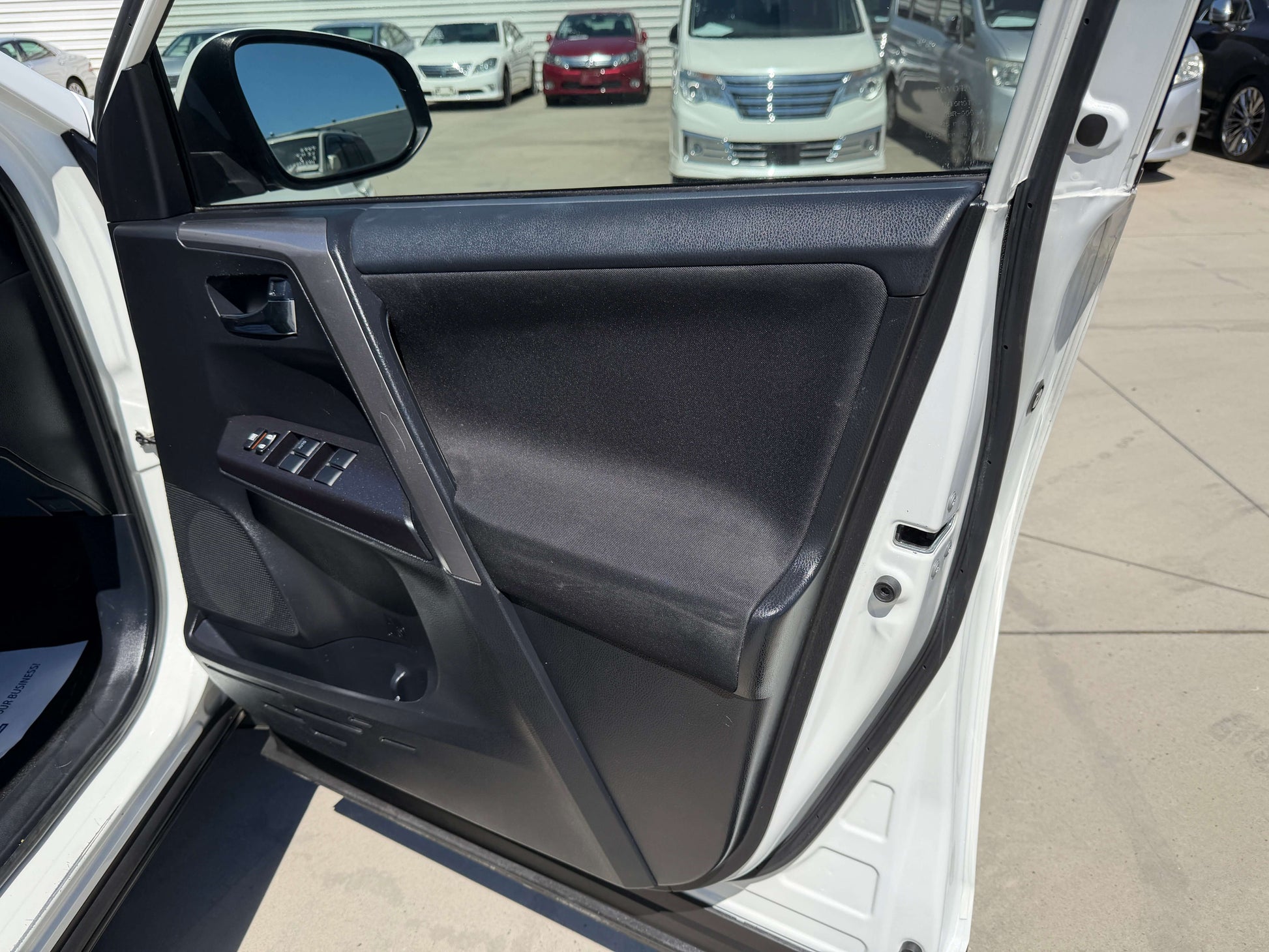 Interior view of a 2016 Toyota RAV4 door showing controls and handle.