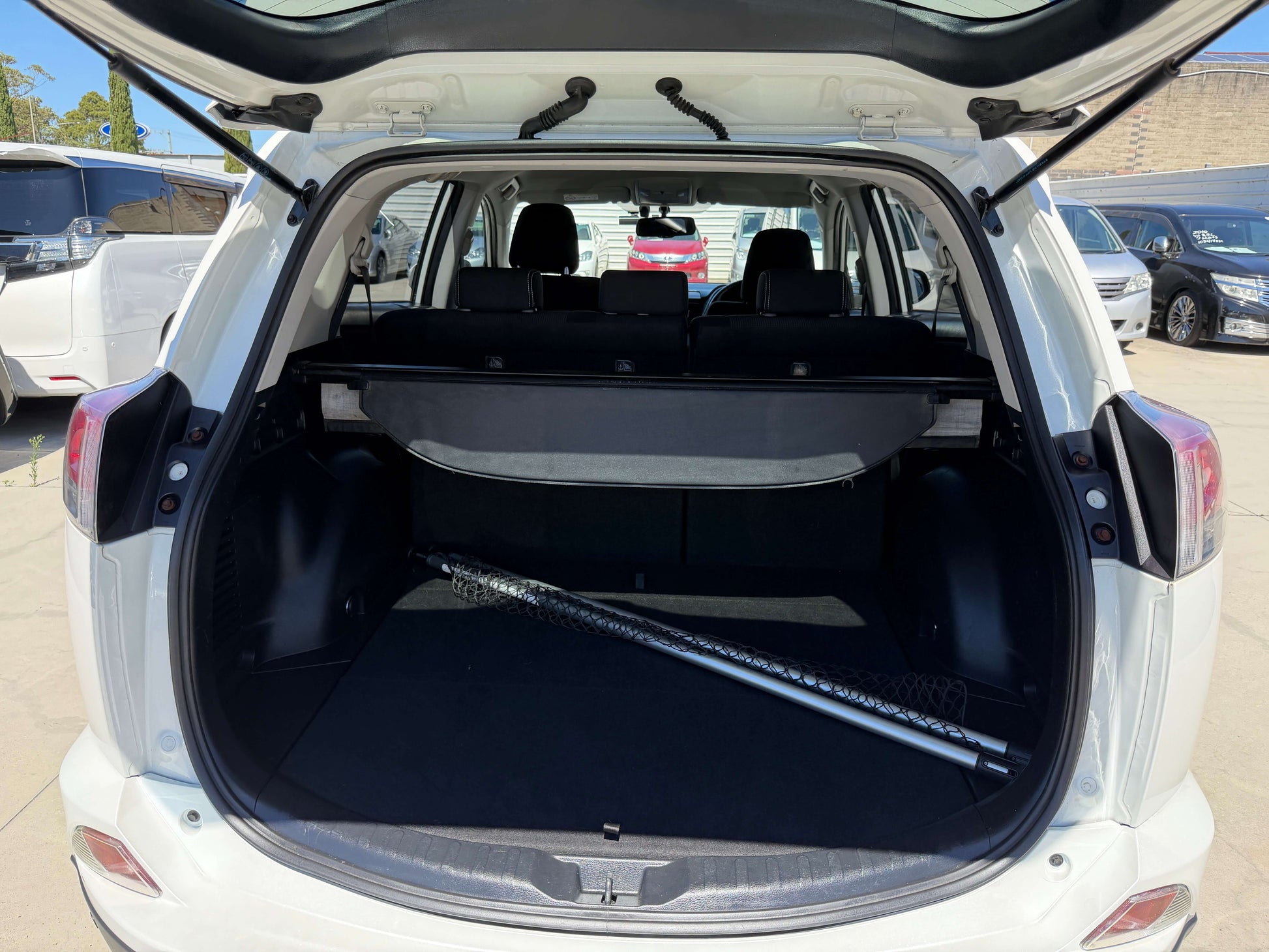 2016 Toyota RAV4 interior view of cargo space showing black upholstery and a silver item in the trunk.