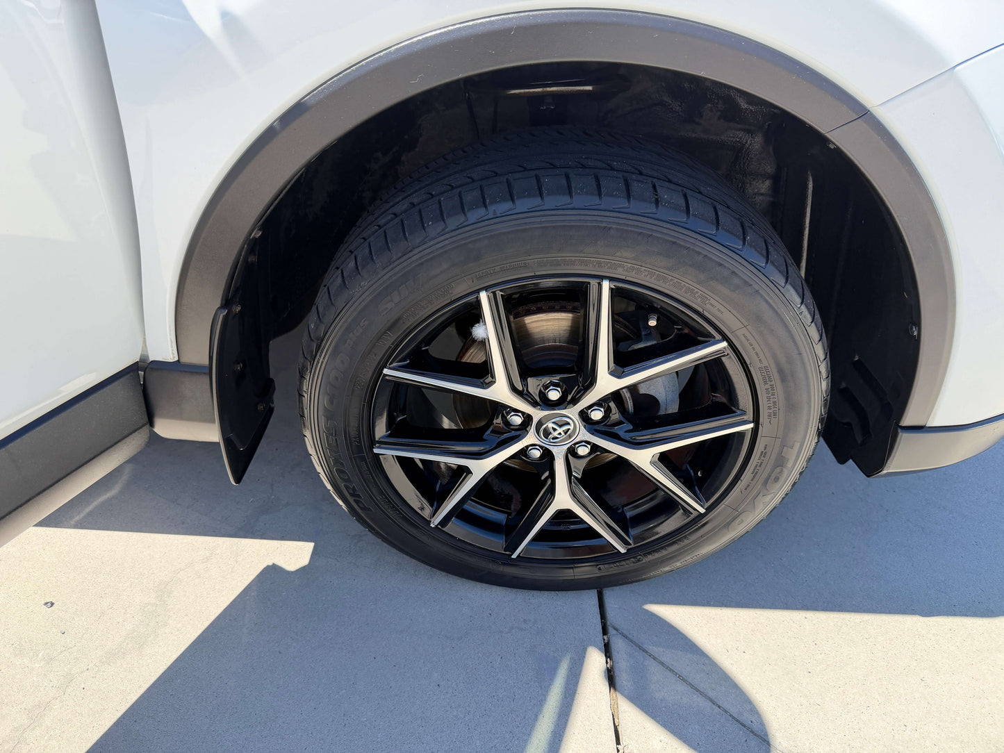 2016 Toyota RAV4 wheel close-up showing black alloy rim and tire on a white SUV.