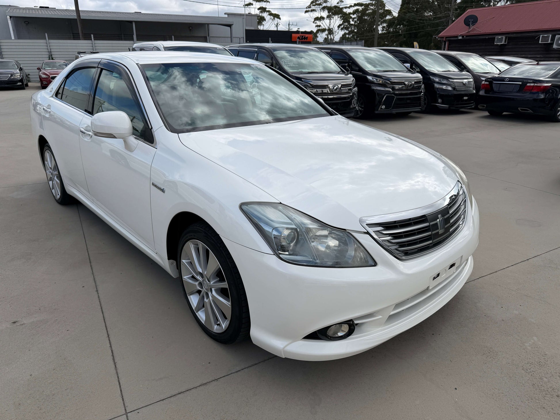 2009 Toyota Crown V6 3.5L Hybrid G-Edition Luxury Sedan in white parked prominently.