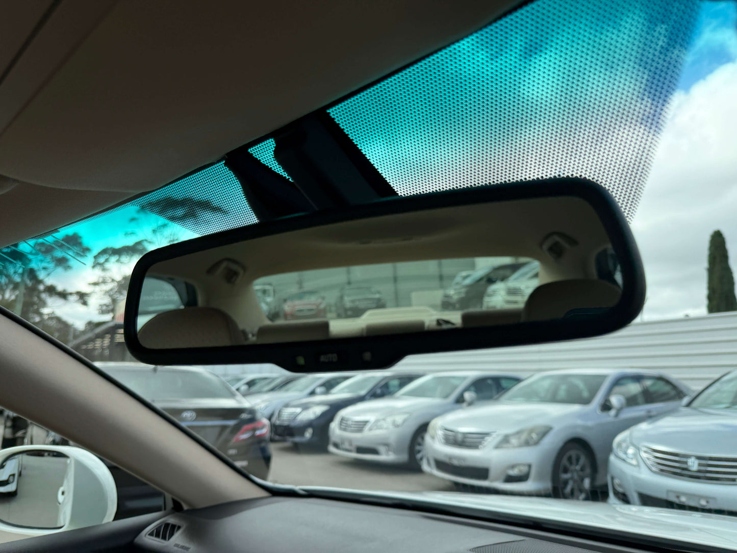 2009 Toyota Crown V6 3.5L Hybrid Interior view of a rearview mirror in a vehicle showcasing parked cars in the background.