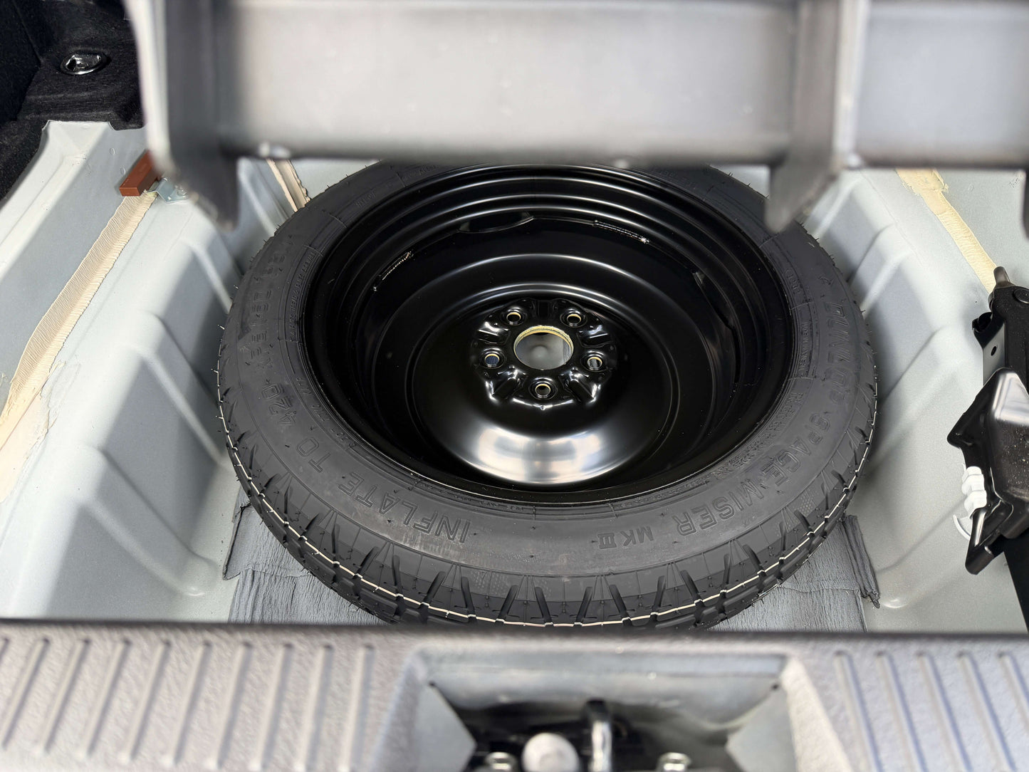 2009 Toyota Crown V6 3.5L Hybrid spare tire stored in trunk compartment for easy access.