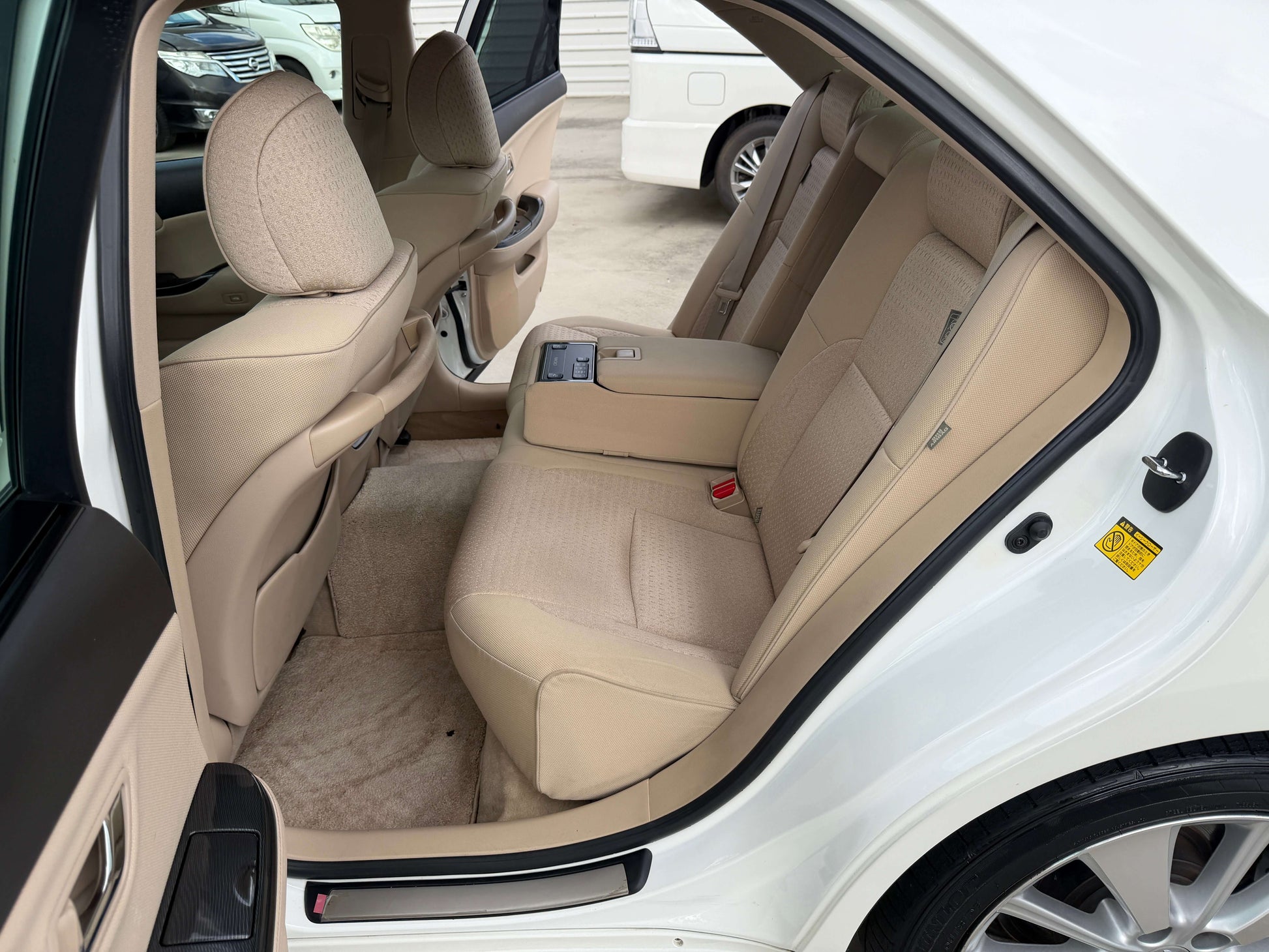 Interior view of the back seat of a 2009 Toyota Crown V6 3.5L Hybrid showing beige leather upholstery.