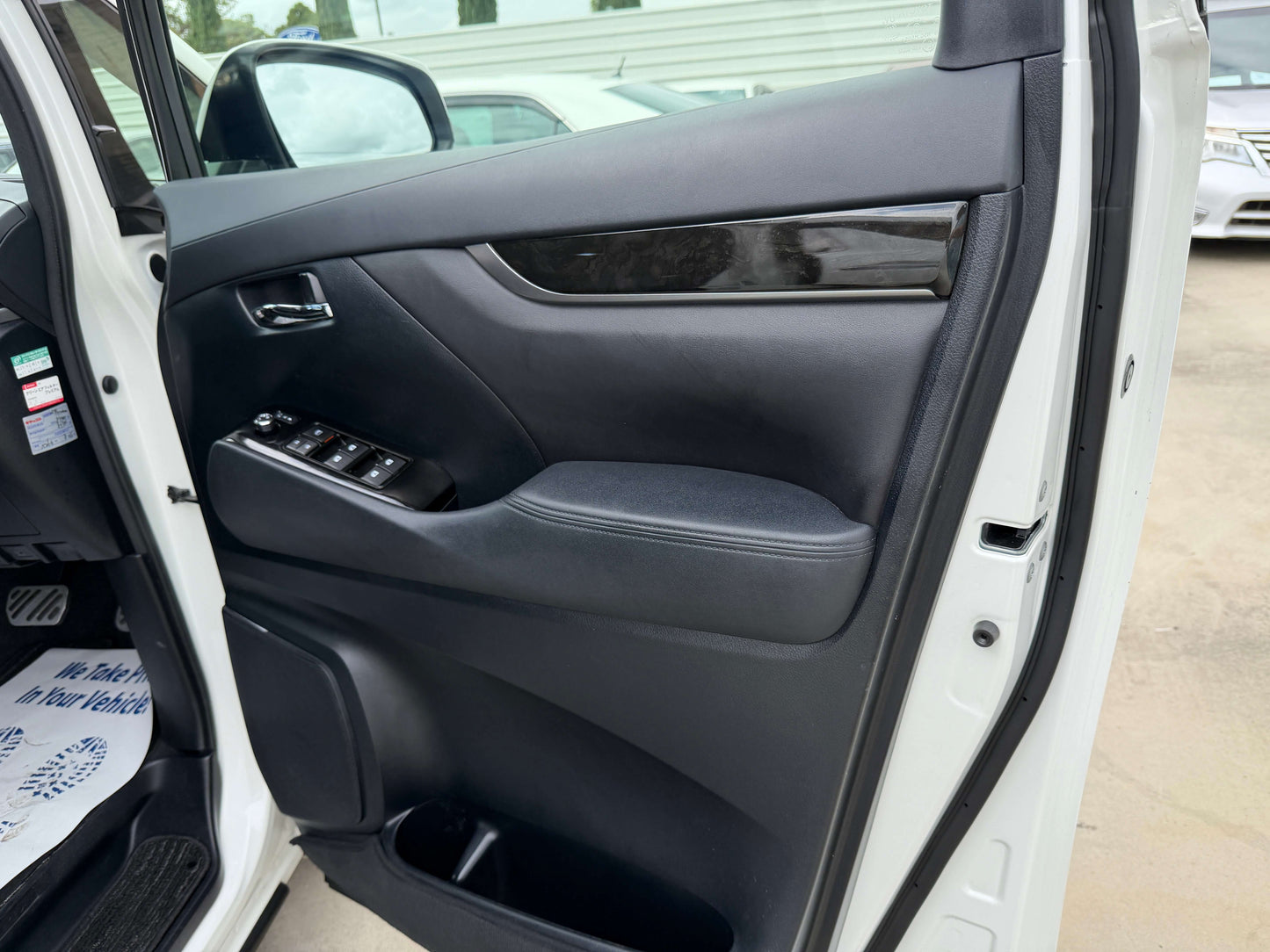 Interior view of the 2016 Toyota Alphard 2.5L door panel showcasing luxury features and controls.