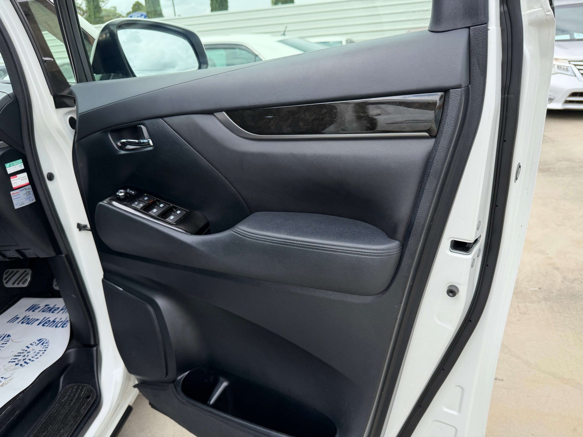 Interior view of the 2016 Toyota Alphard 2.5L door panel showcasing luxury features and controls.