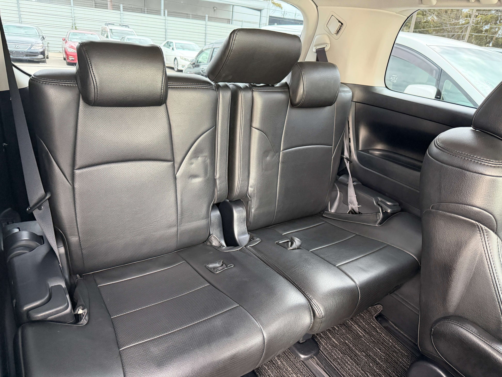 Interior view of the rear seating in a 2016 Toyota Alphard 2.5L, featuring luxurious black leather upholstery.