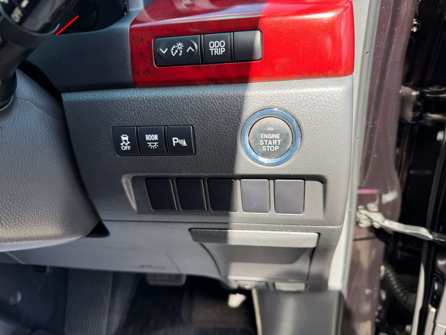 Interior dashboard controls of a 2009 Toyota Vellfire 2.4L, featuring engine start/stop button and various switches.
