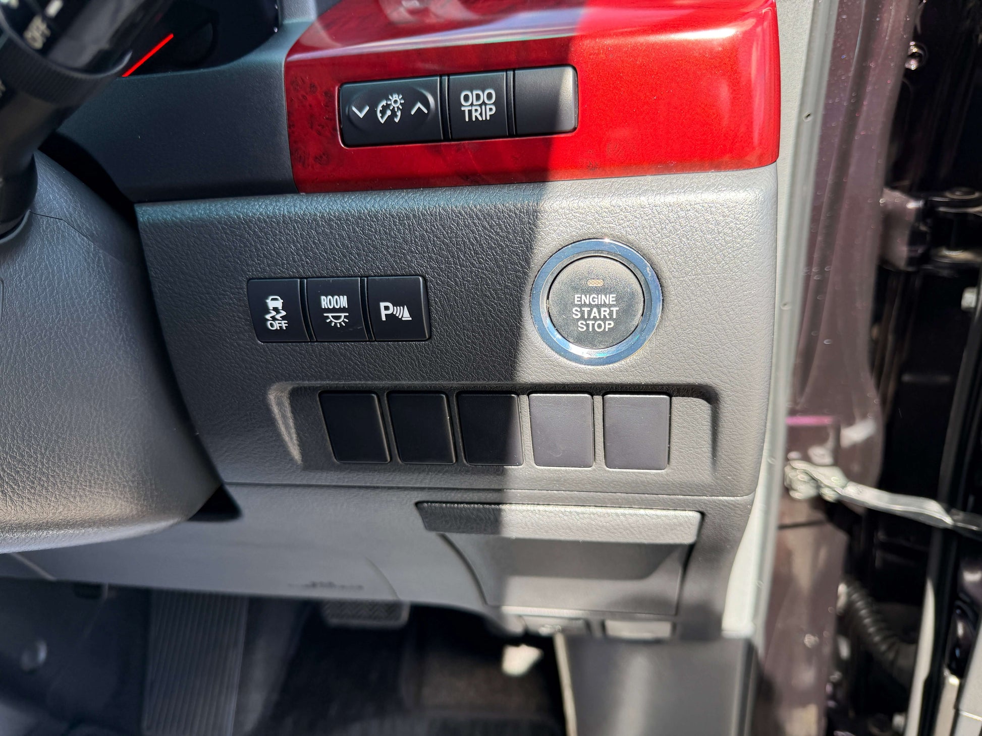 Interior dashboard controls of a 2009 Toyota Vellfire 2.4L, featuring engine start/stop button and various switches.