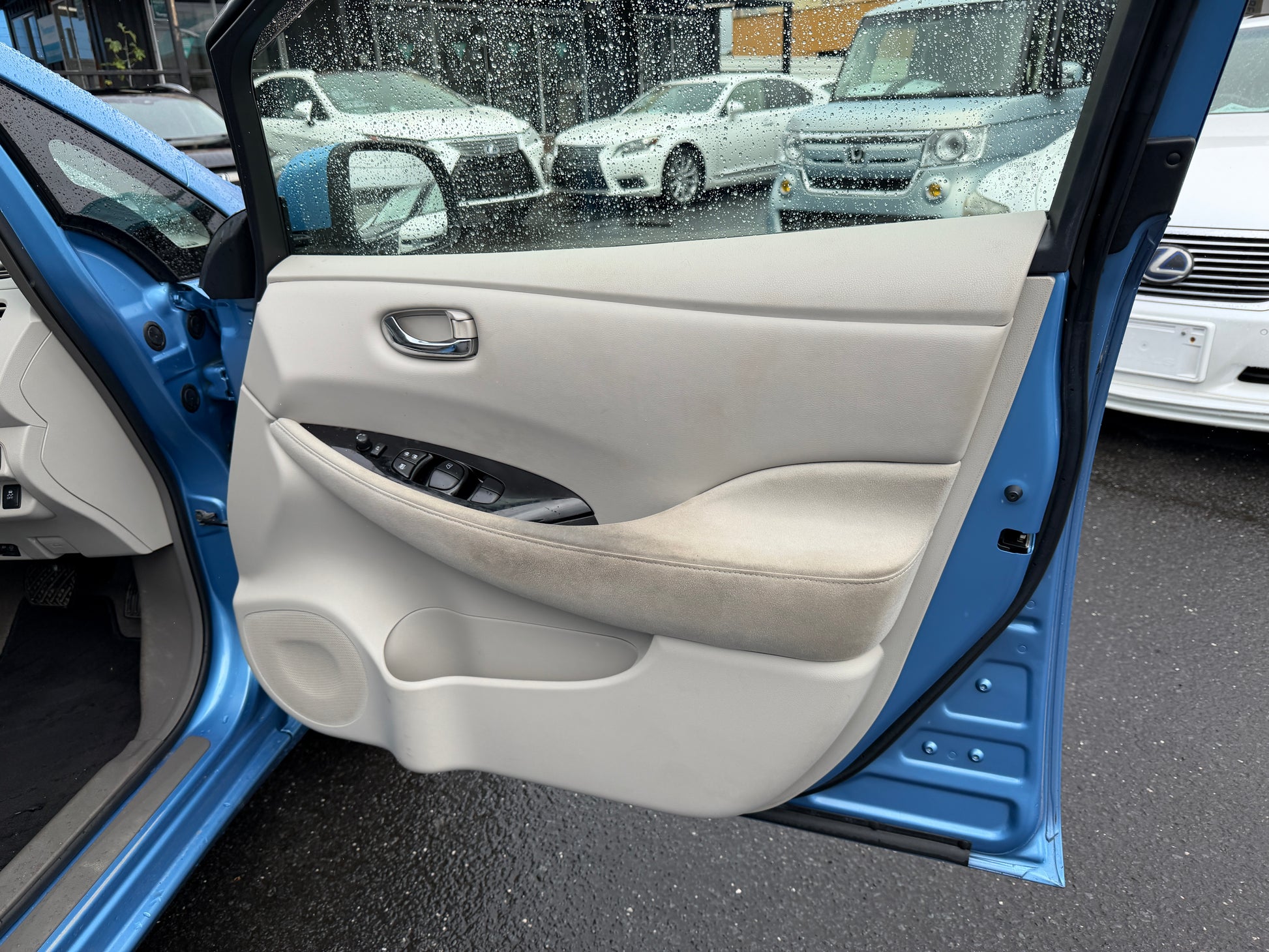 Interior view of 2015 Nissan Leaf 24kW G-Edition Full Electric door panel with controls and fabric trim.