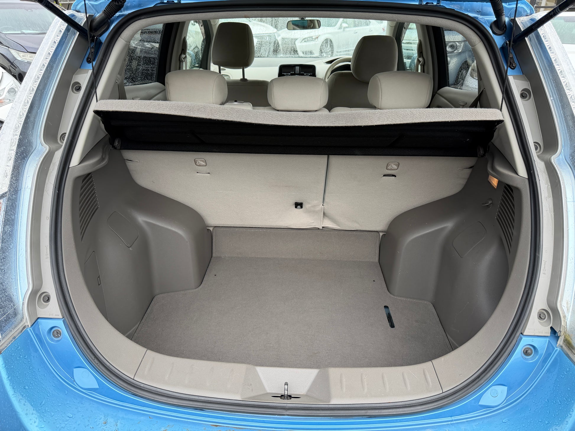 Interior view of the spacious trunk of the 2015 Nissan Leaf 24kW G-Edition Full Electric with beige carpet.