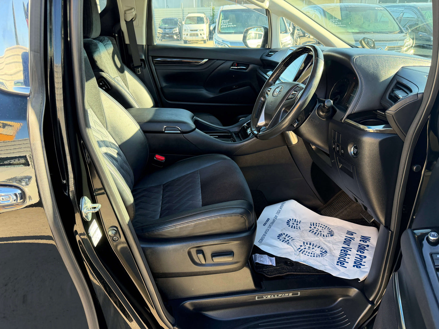 Interior view of a 2016 Toyota Vellfire V6 3.5L showcasing black leather seats and modern dashboard features.