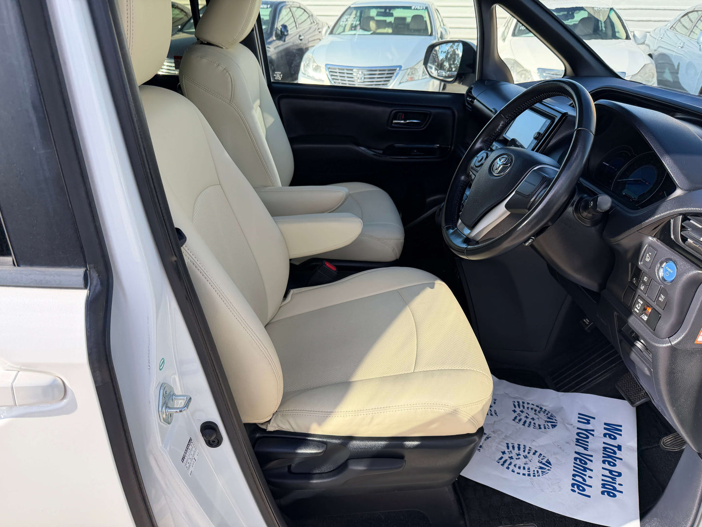 Interior view of a 2017 Toyota Noah 1.8L Hybrid G Premium Edition showing beige seats and dashboard.
