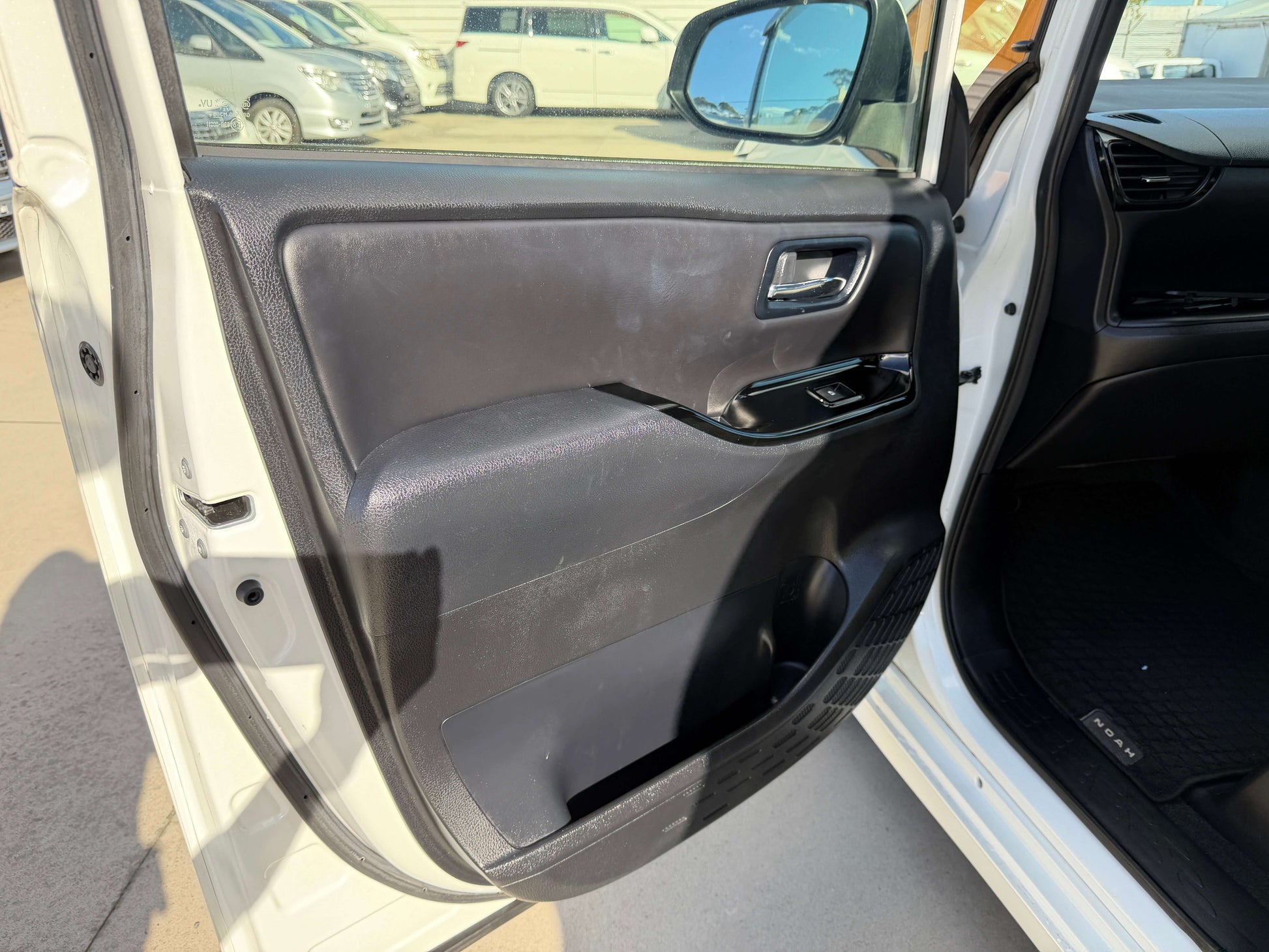 Interior view of the driver's side door of a 2017 Toyota Noah 1.8L Hybrid featuring sleek design and controls.