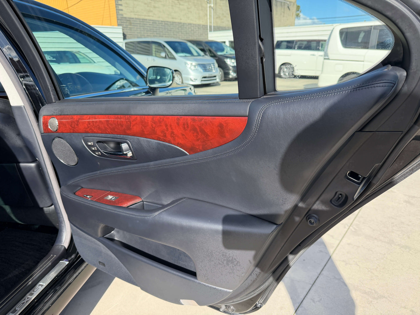 Interior view of the 2007 Lexus LS600hL AWD V8 5.0L Hybrid door panel, featuring luxurious wood trim and controls.