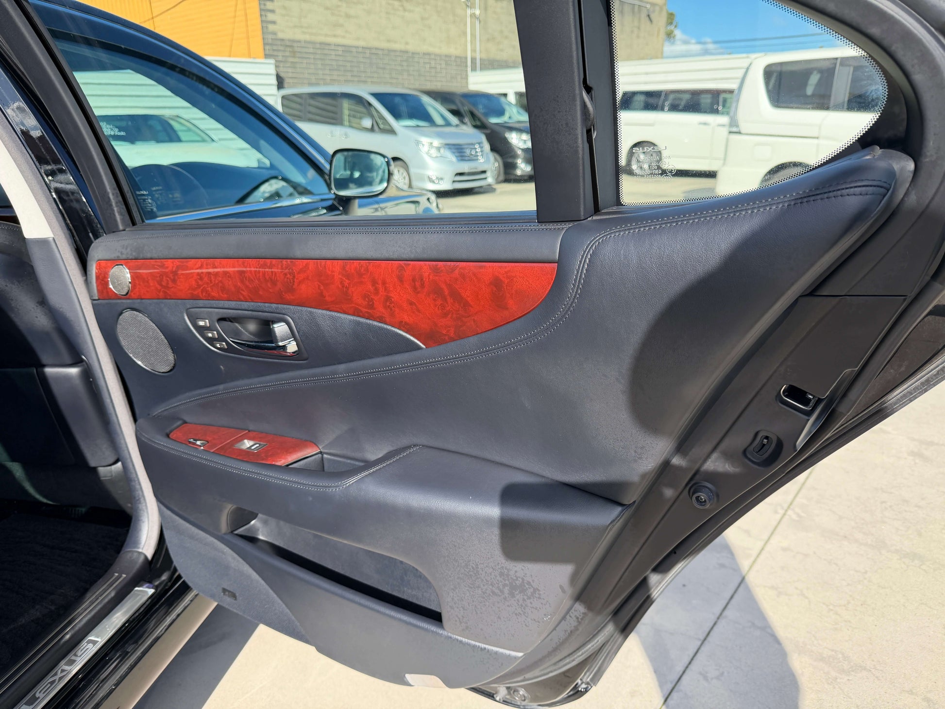 Interior view of the 2007 Lexus LS600hL AWD V8 5.0L Hybrid door panel, featuring luxurious wood trim and controls.