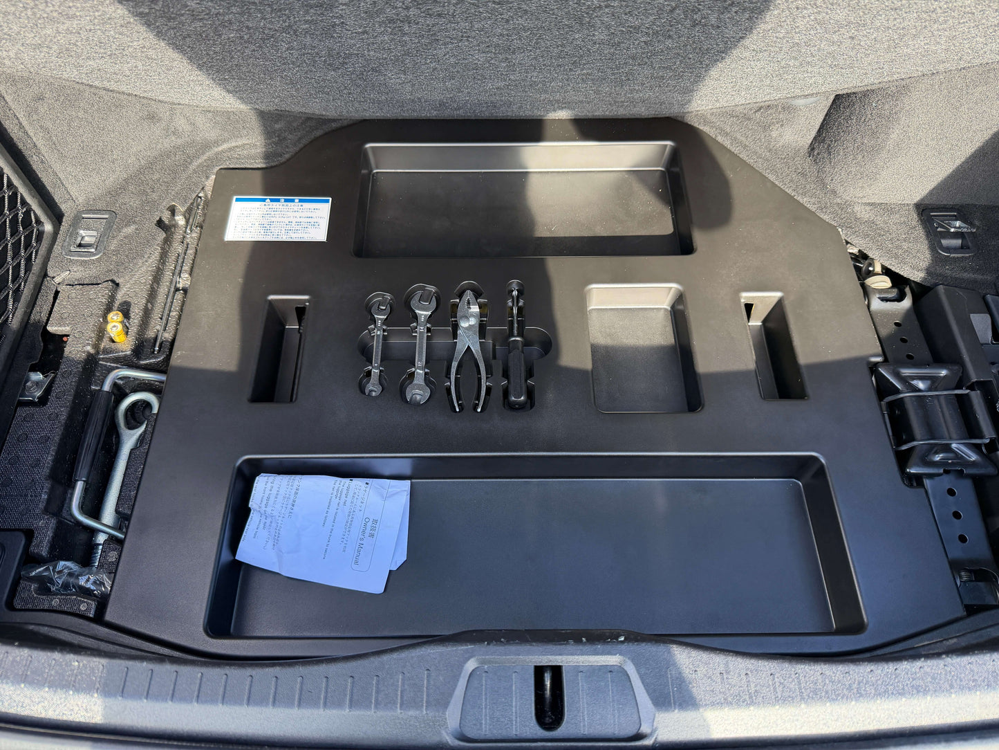 2007 Lexus LS600hL AWD V8 5.0L Hybrid Interior storage compartment of a vehicle with tools and documentation organized in the trunk area.