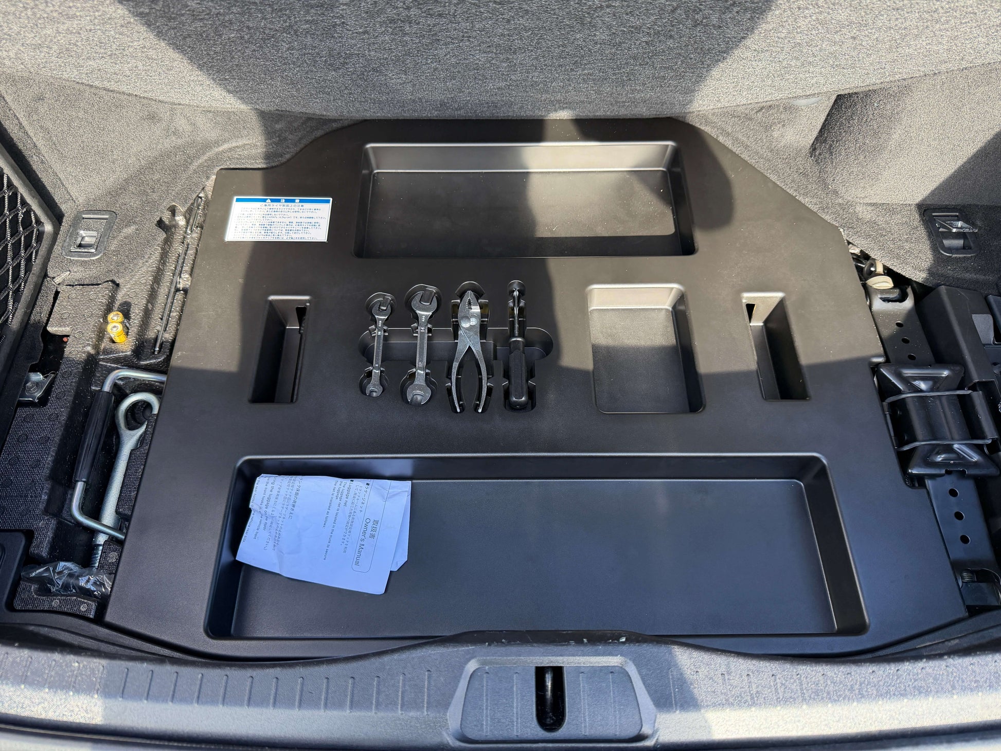 2007 Lexus LS600hL AWD V8 5.0L Hybrid Interior storage compartment of a vehicle with tools and documentation organized in the trunk area.