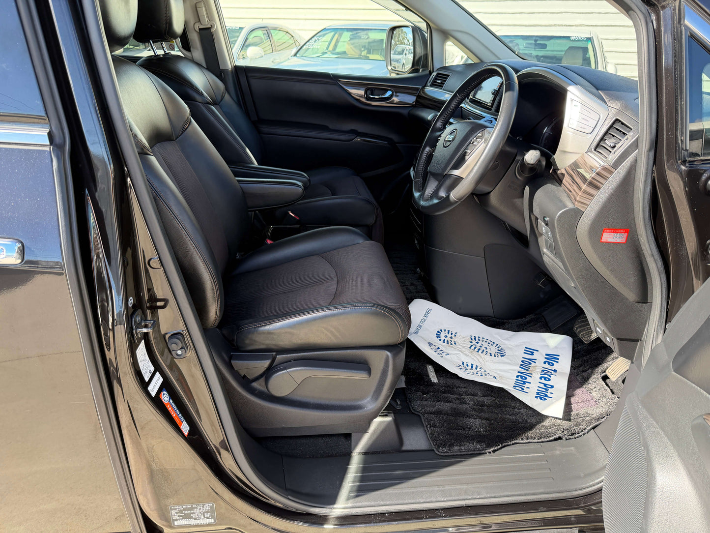 Interior view of 2015 Nissan Elgrand 2.5L 250 Highway Star showing driver and passenger seats in black leather.