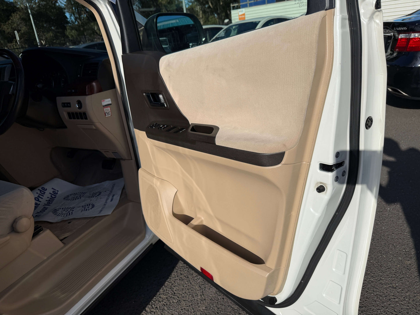 Interior view of the 2009 Toyota Alphard 2.4L door panel, showcasing beige upholstery and controls.