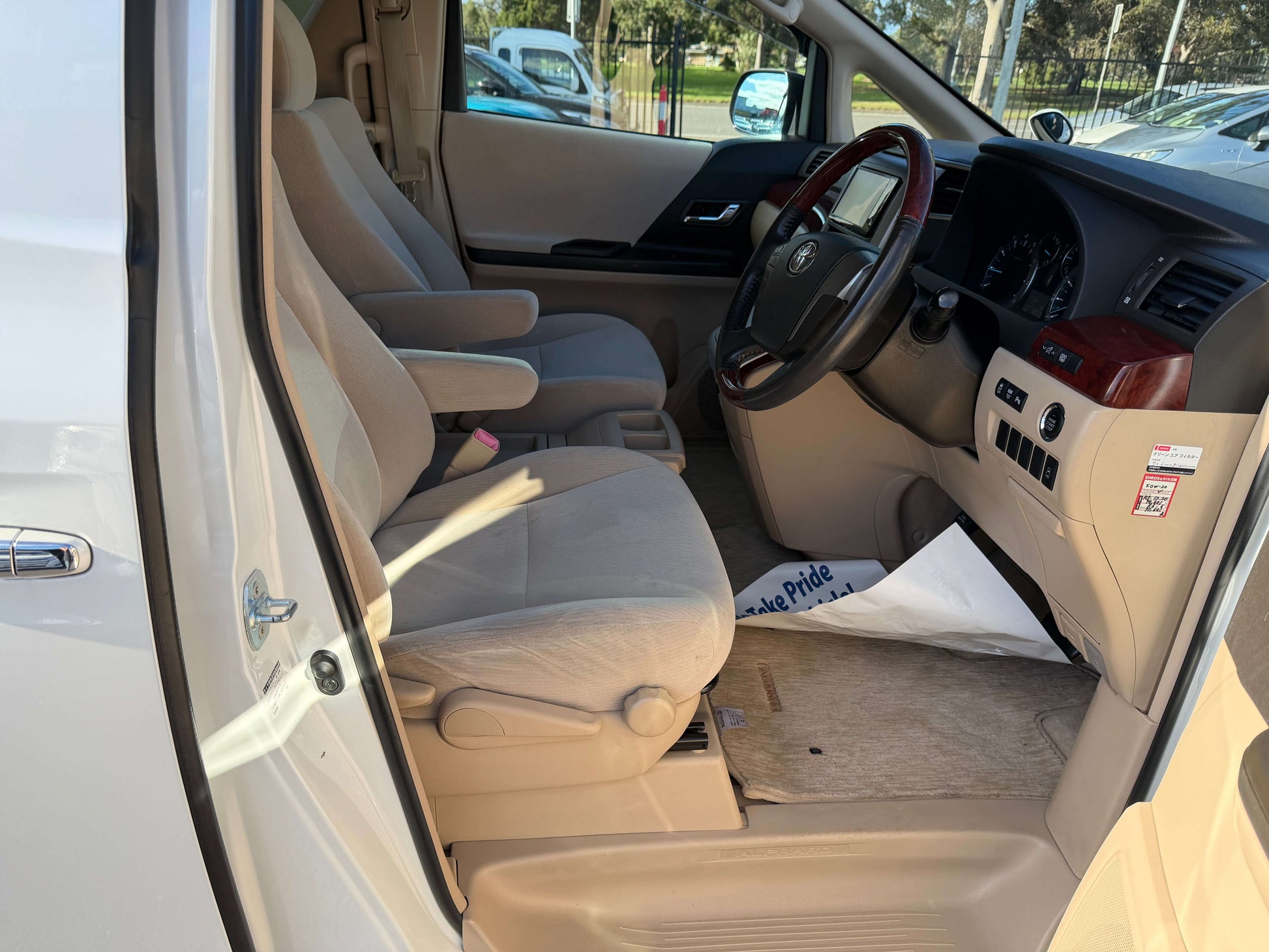 Interior view of a 2009 Toyota Alphard 2.4L with beige upholstery and dashboard, showcasing luxury seating and controls.