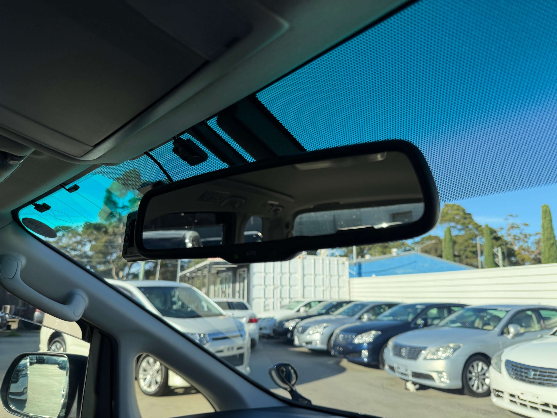 2014 Toyota Vellfire 2.4L Interior view of a car's rearview mirror with parked vehicles in the background.