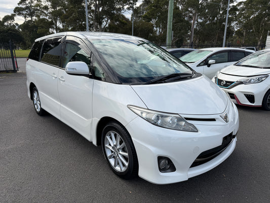 2009 Toyota Estima 2.4L 4WD Aeras Edition pearl white people mover front three-quarter view showing projector headlamps and factory alloy wheels
