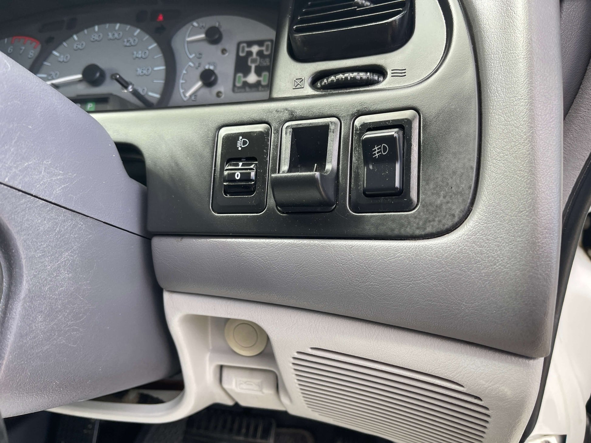 Interior dashboard controls of a 2006 Mitsubishi Delica V6 3.0L 4WD, highlighting lights and switches.