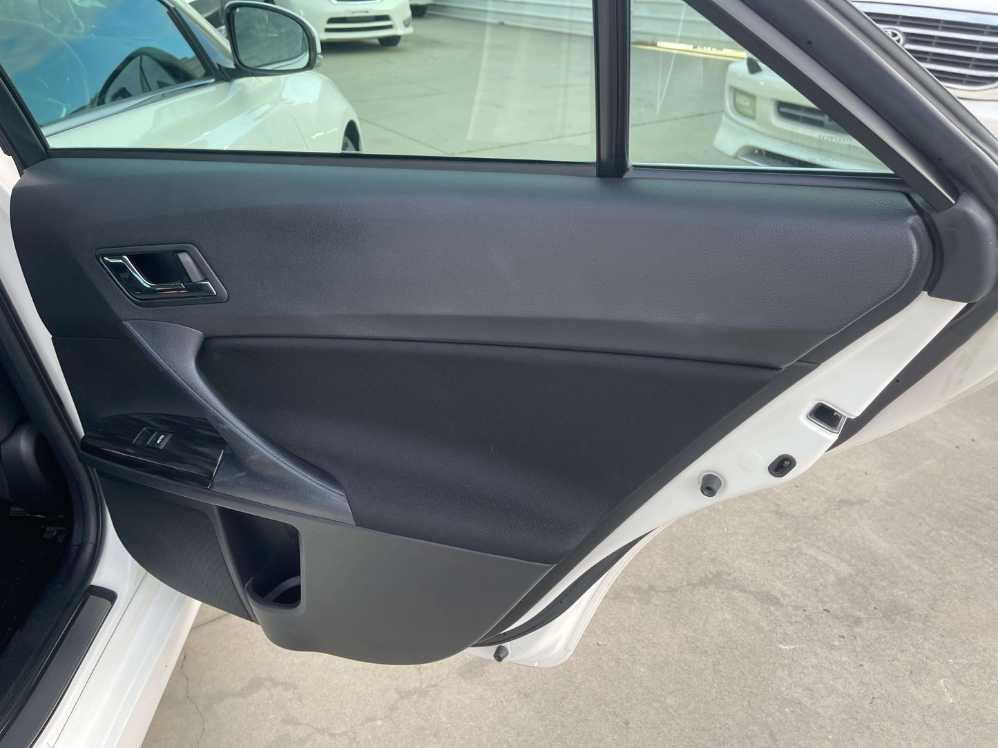Interior view of the 2011 Toyota Mark X door panel showcasing sleek black design and window control features.