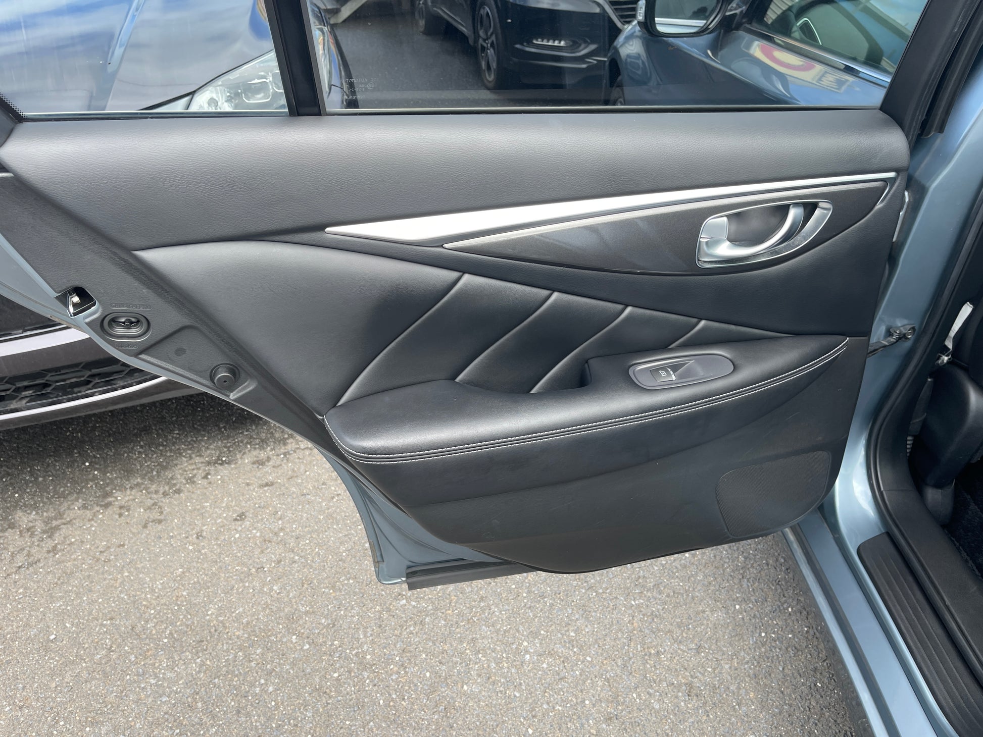 Interior view of the driver's side door of a 2016 Nissan Skyline V6 3.5L Hybrid, featuring sleek black leather trim.
