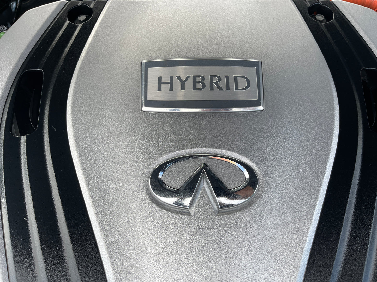 Close-up of the engine cover featuring the word HYBRID and Infiniti logo in a 2016 Nissan Skyline V6 3.5L Hybrid.