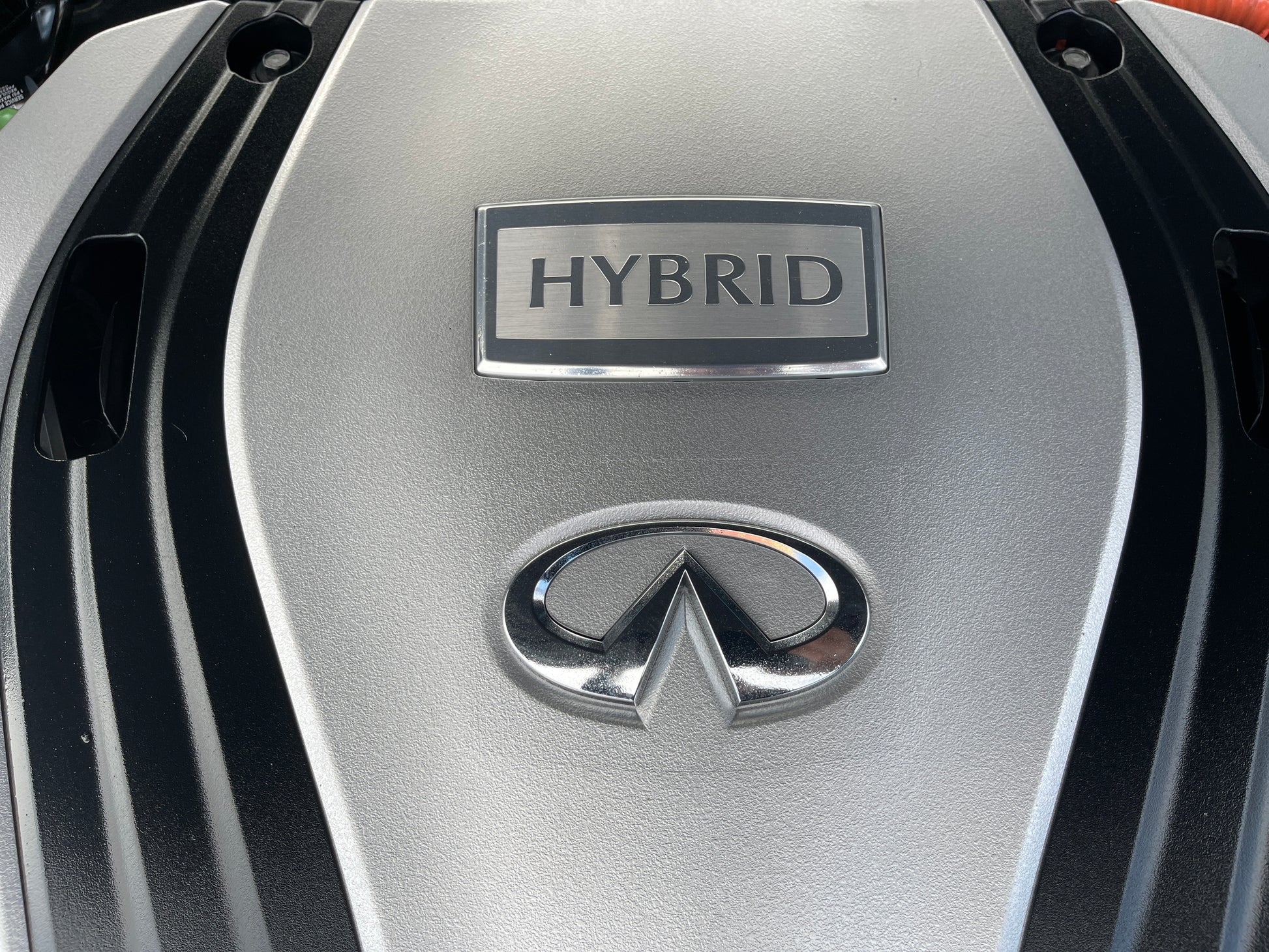 Close-up of the engine cover featuring the word HYBRID and Infiniti logo in a 2016 Nissan Skyline V6 3.5L Hybrid.