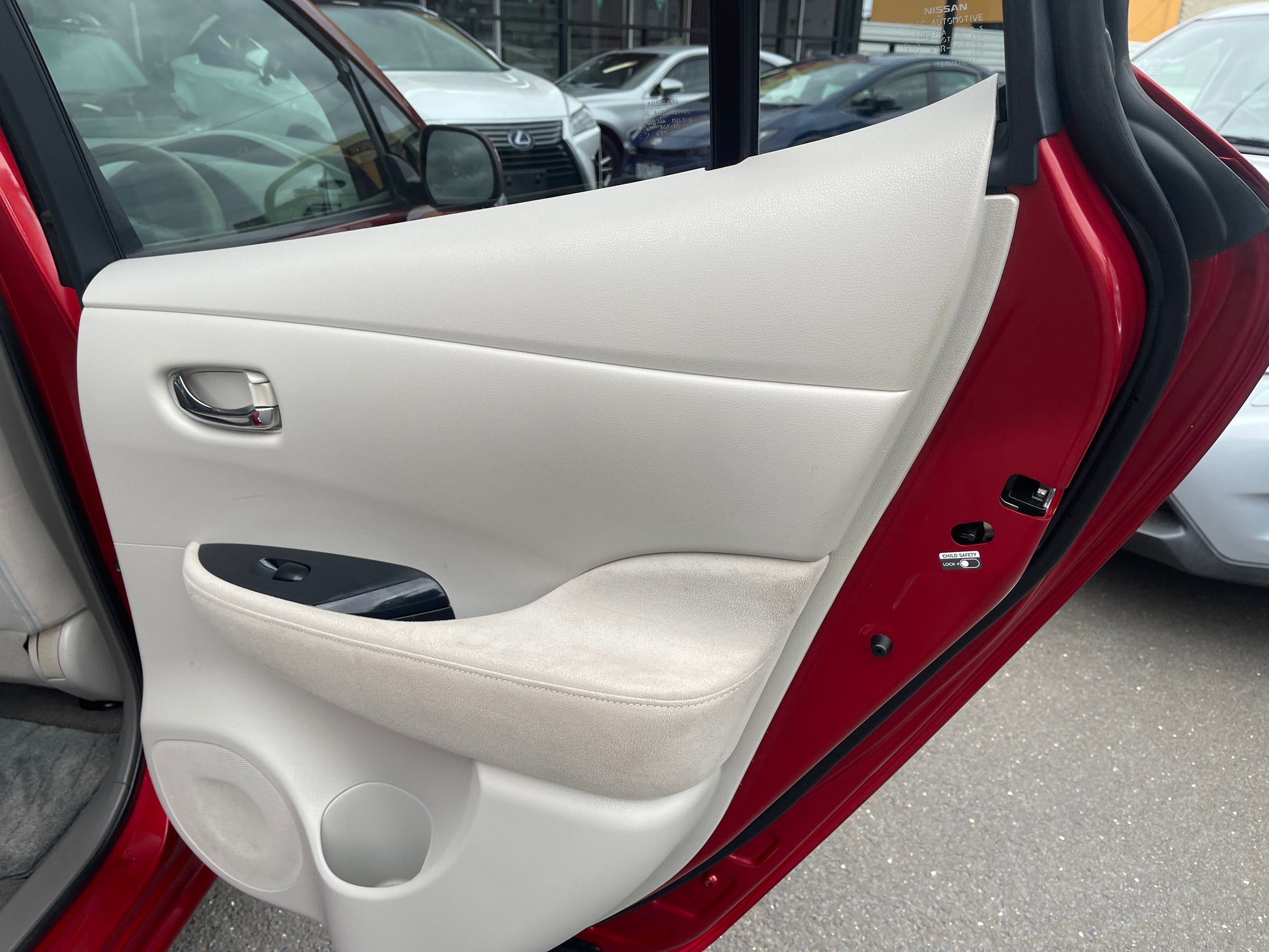 Interior door panel of a 2013 Nissan Leaf 24kW G-Edition Full Electric, showing plush upholstery and controls.