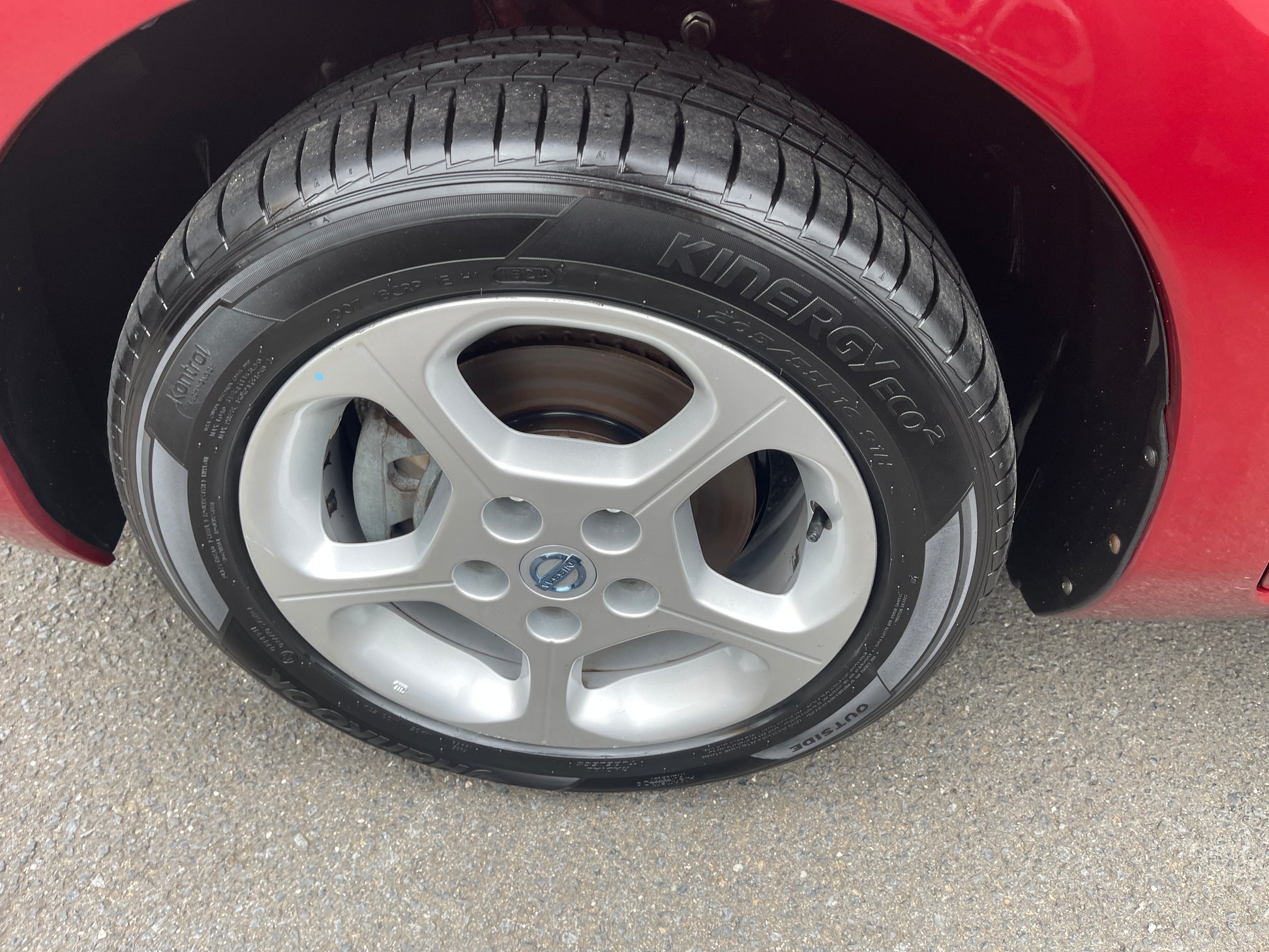Close-up of 2013 Nissan Leaf 24kW G-Edition Full Electric wheel and tire mounted on a red vehicle.