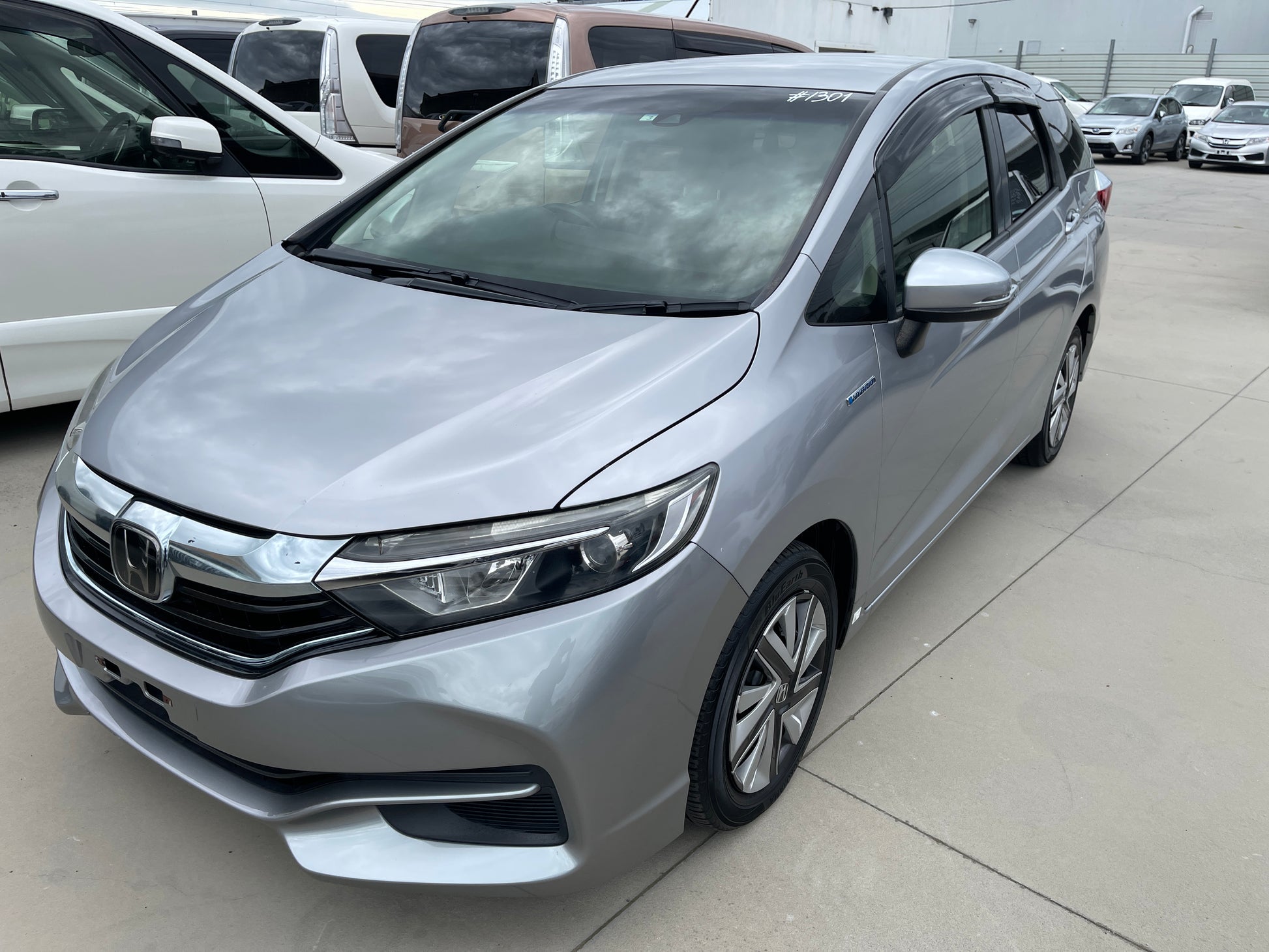 2018 Honda Shuttle 1.5 Hybrid X Honda Sensing Edition silver car parked in a lot, showcasing sleek design and modern features.