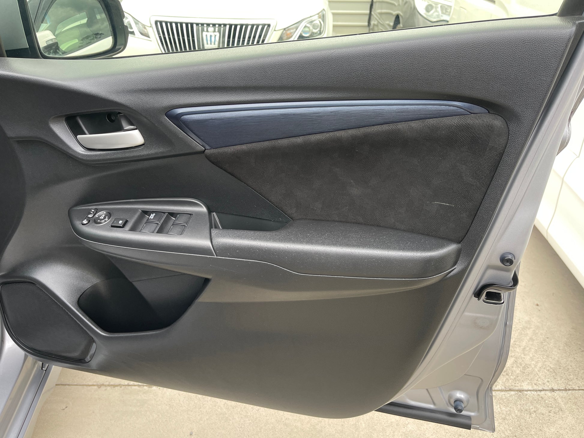 Interior door panel of a 2018 Honda Shuttle 1.5 Hybrid, featuring control buttons and sleek design.