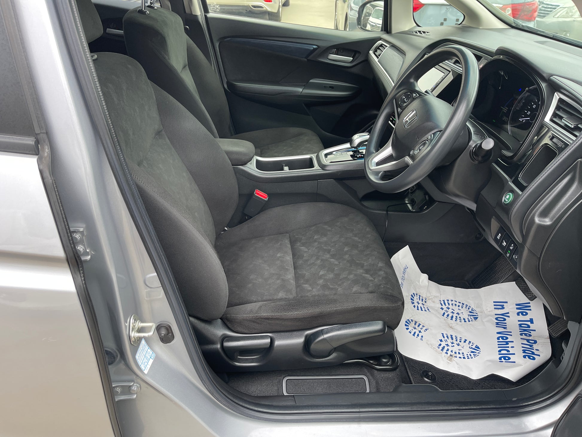 Interior view of 2018 Honda Shuttle 1.5 Hybrid X showing black seats and dashboard features.