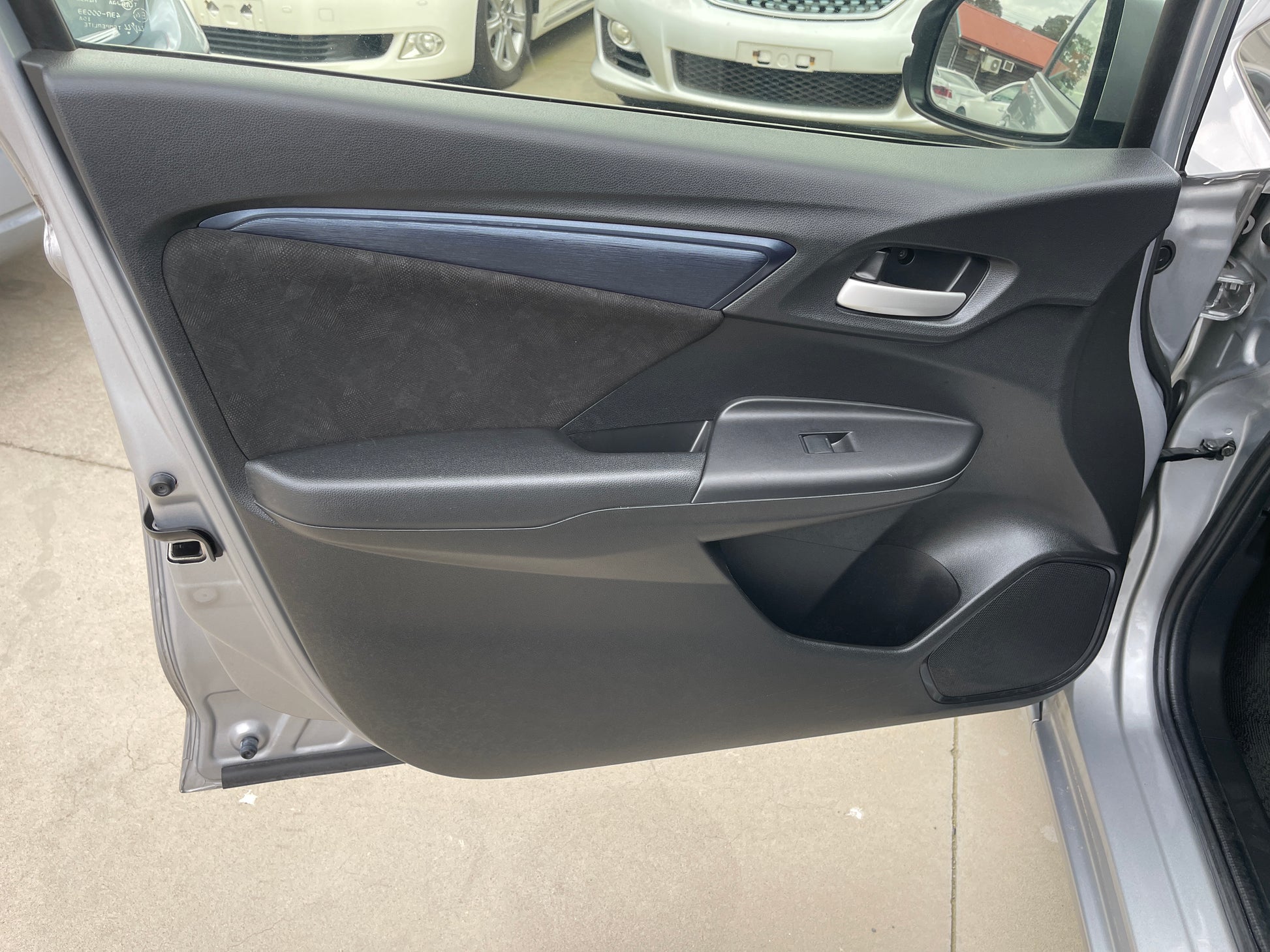 Interior view of the 2018 Honda Shuttle 1.5 Hybrid door panel with black trim and controls.